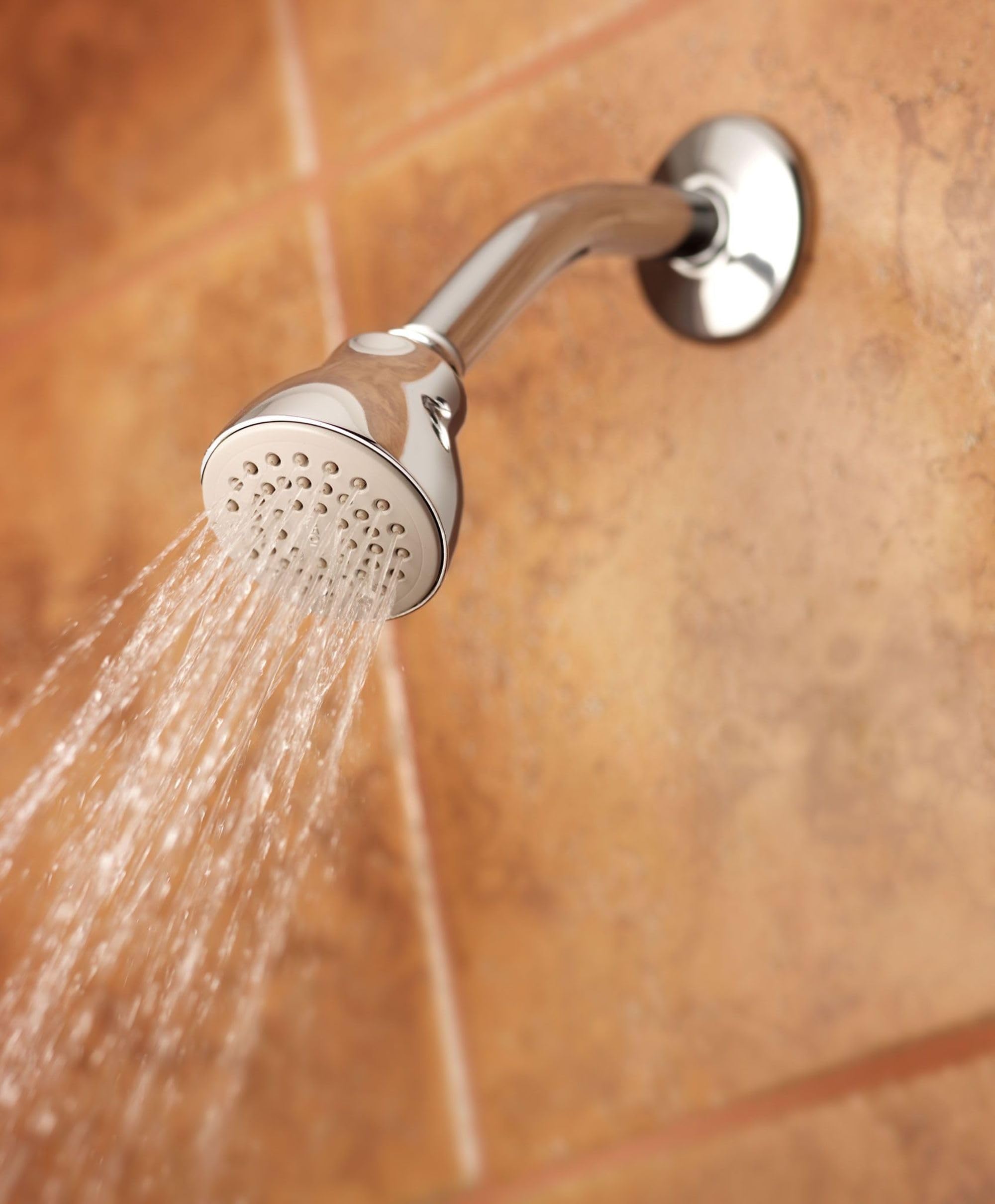 Chrome and brushed nickel shower head with multiple spray holes mounted on wall, actively dispensing water.