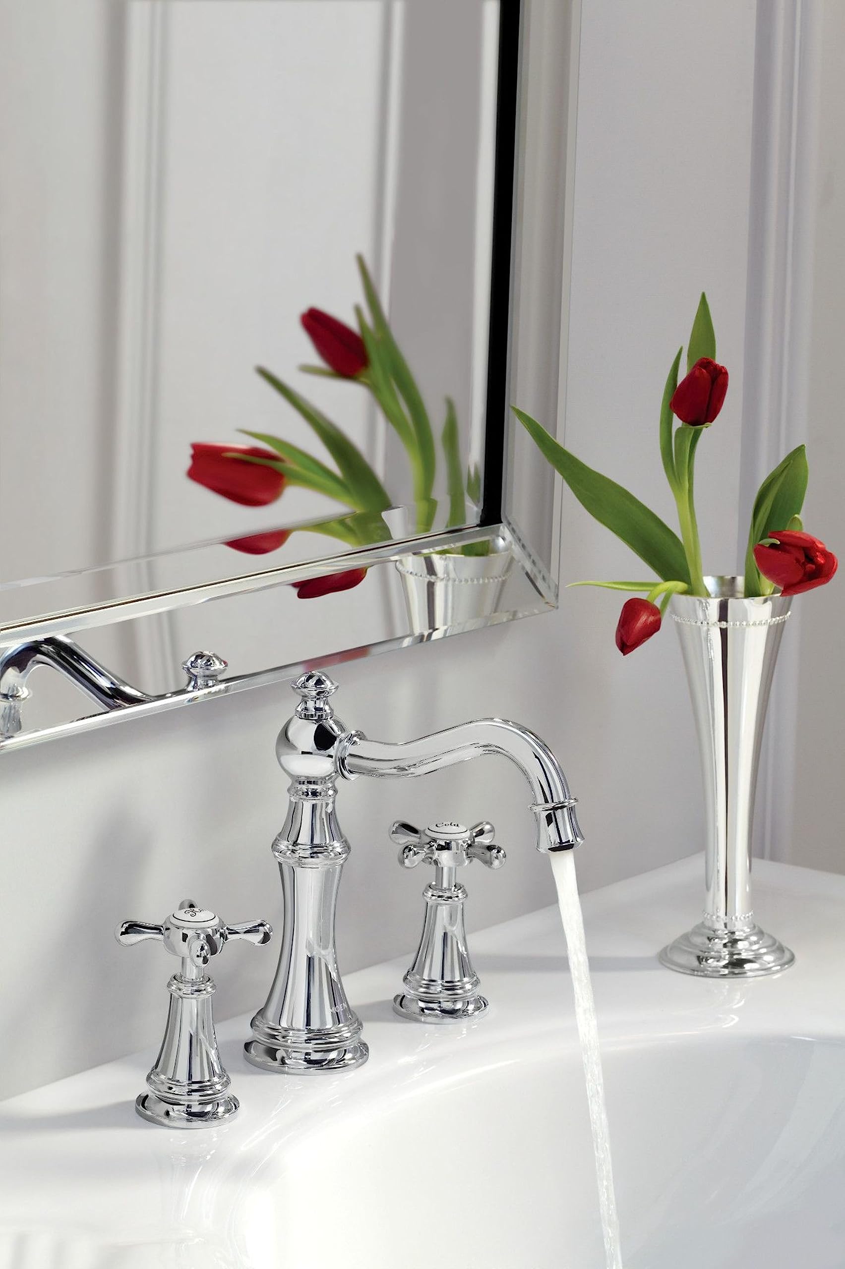 Chrome two-handle lever bathroom faucet with curved spout installed on white sink counter, water running.