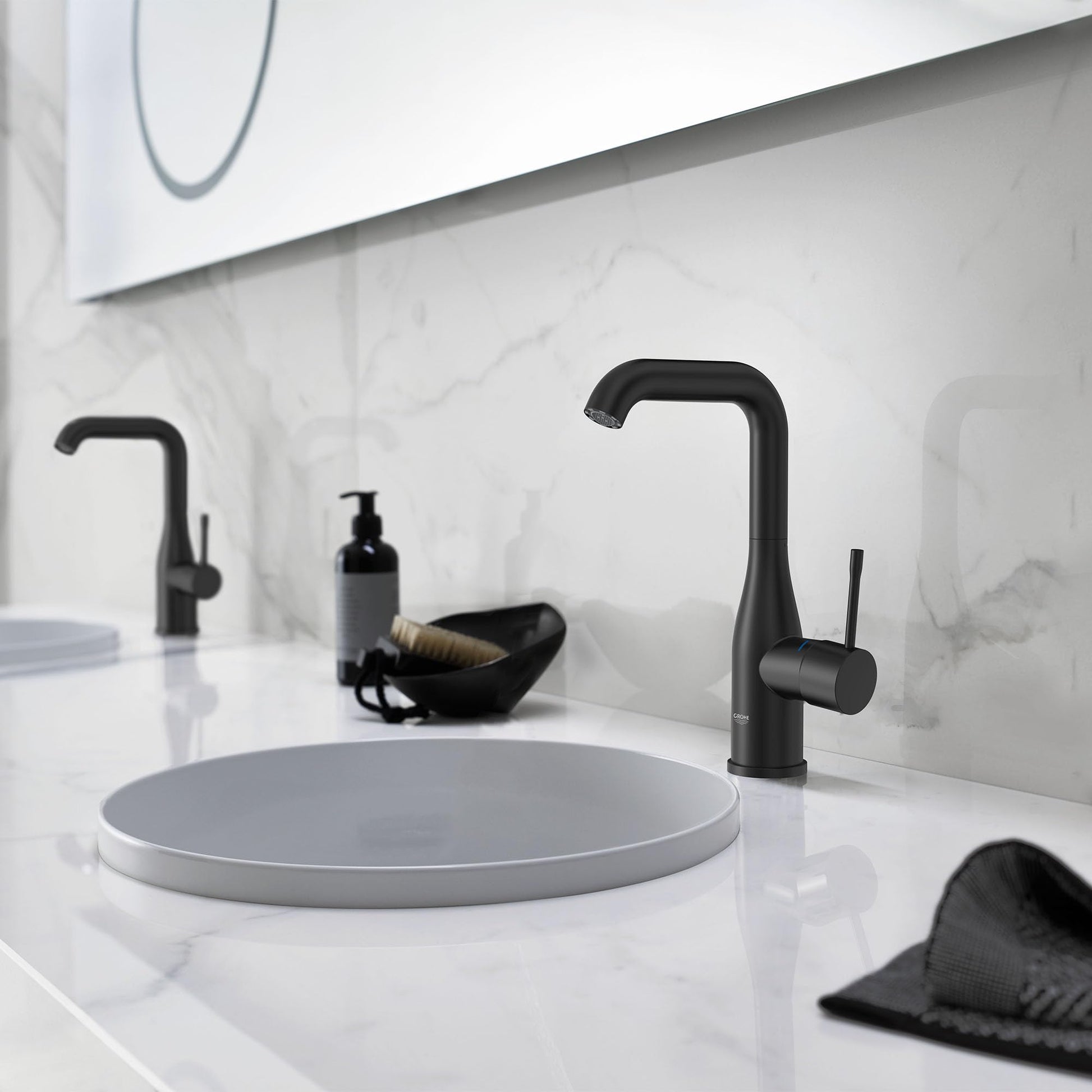 Matte black single-handle bathroom faucet with curved spout mounted on white marble countertop above round sink.
