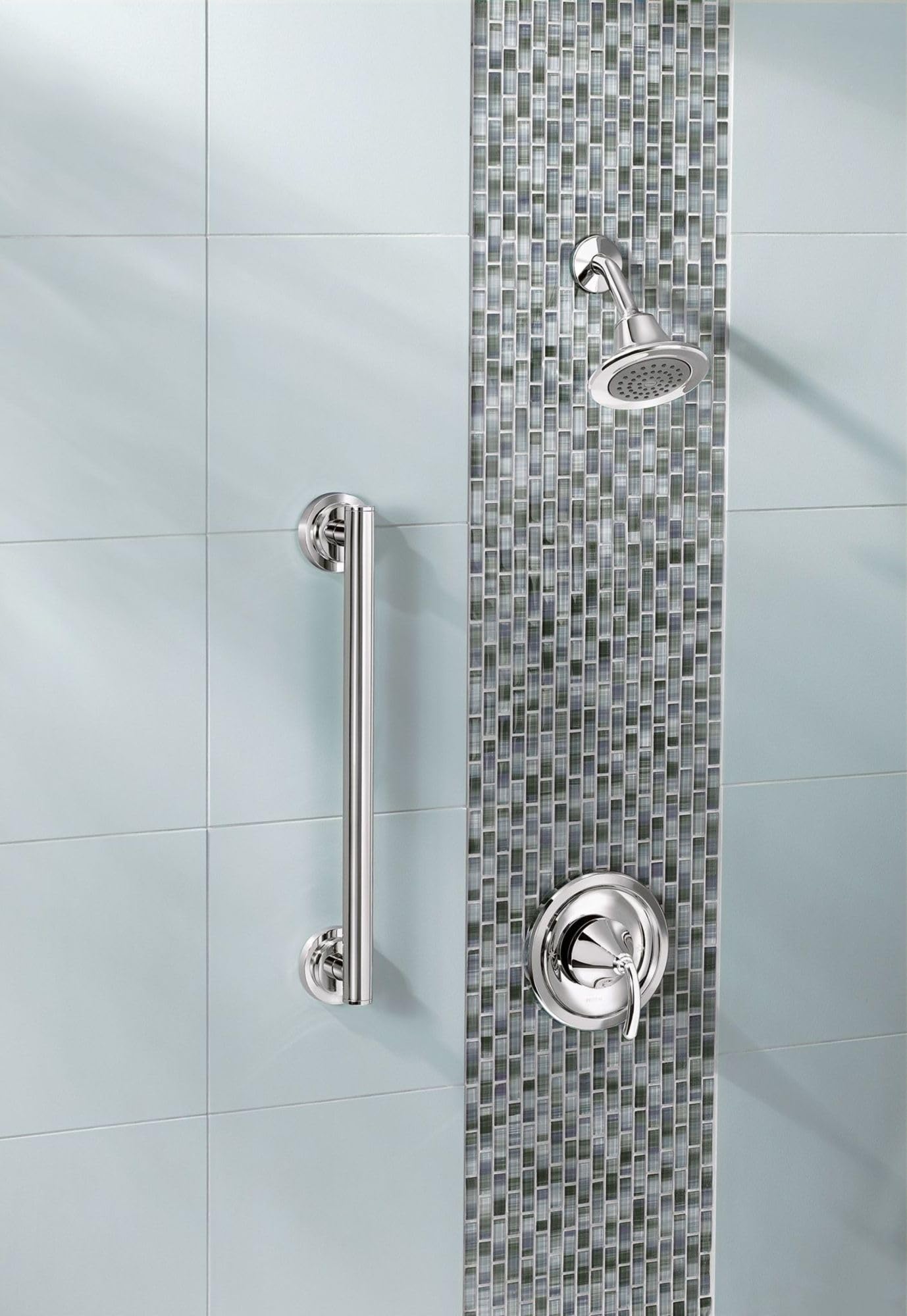 Polished chrome grab bar mounted vertically on bathroom wall tile next to shower fixtures.