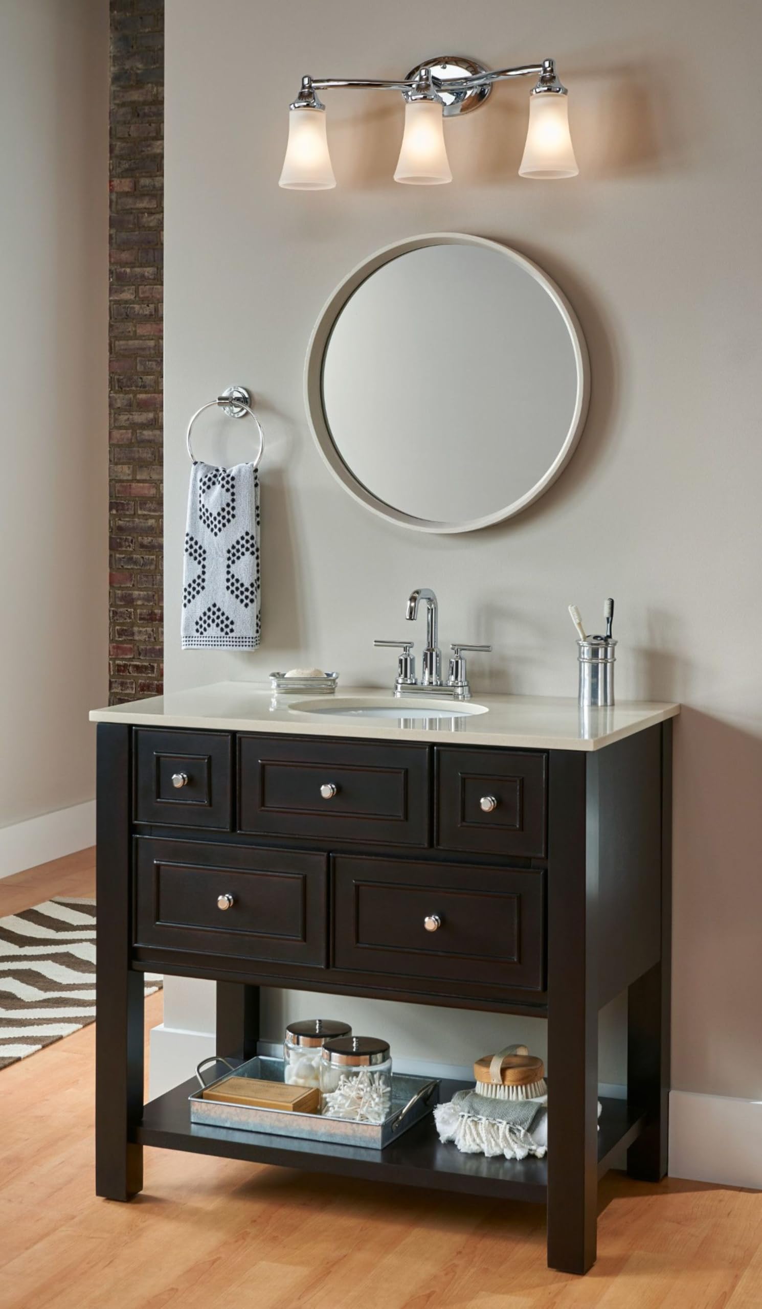 Chrome vanity light fixture with three frosted glass shades mounted above bathroom sink.