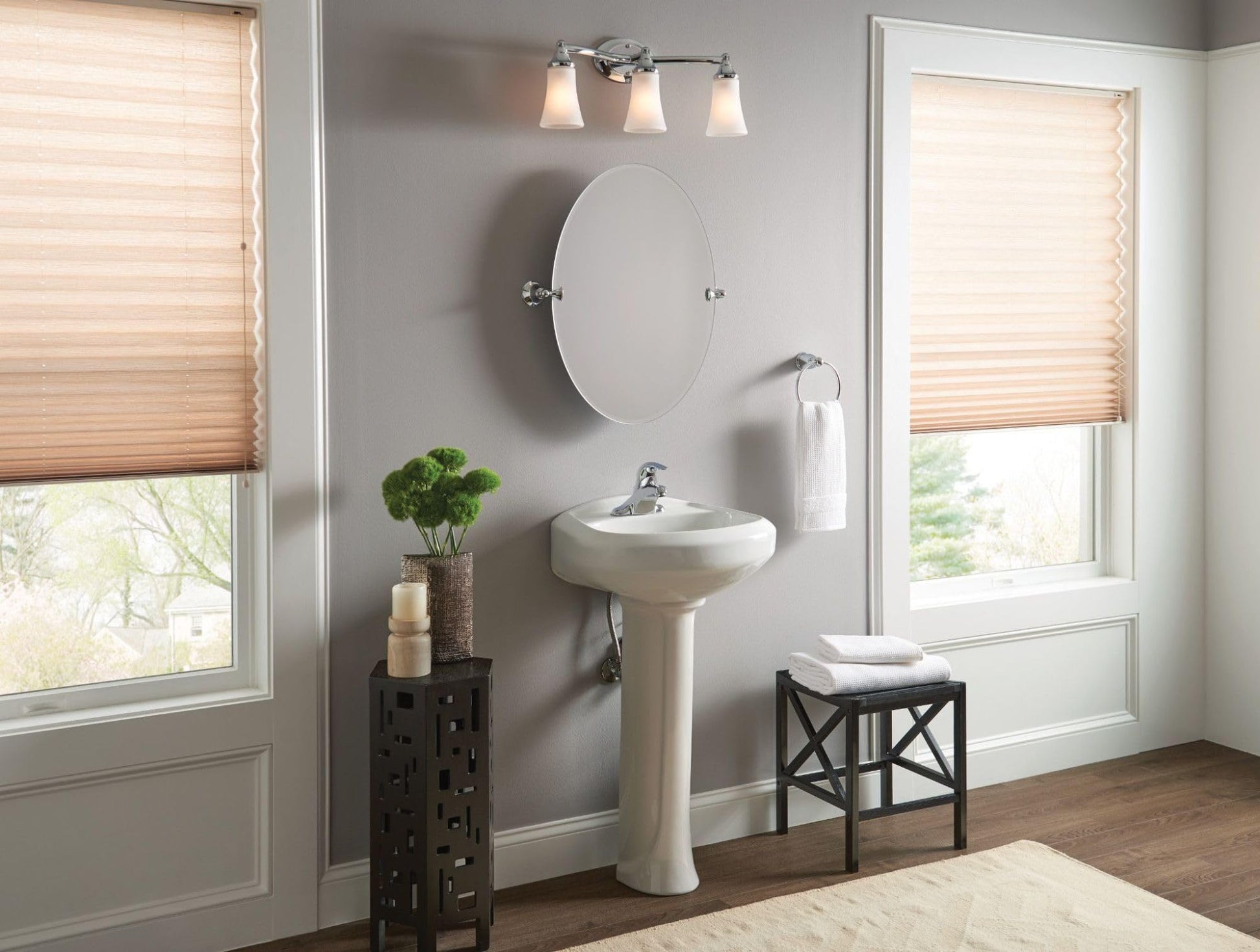 Chrome vanity light fixture with three frosted glass shades mounted above bathroom sink.