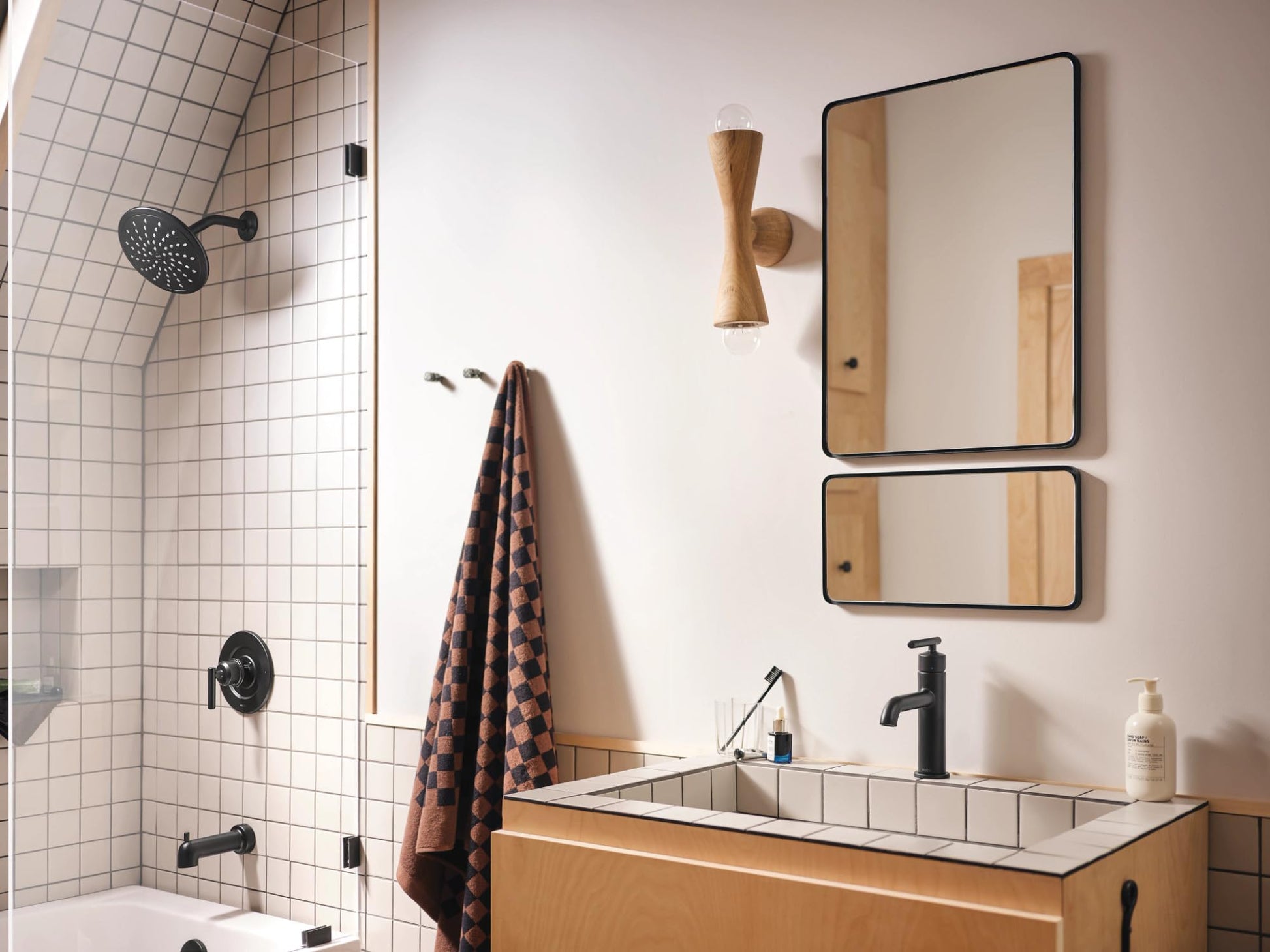Matte black single-handle bathroom sink faucet with curved spout mounted on wooden vanity.