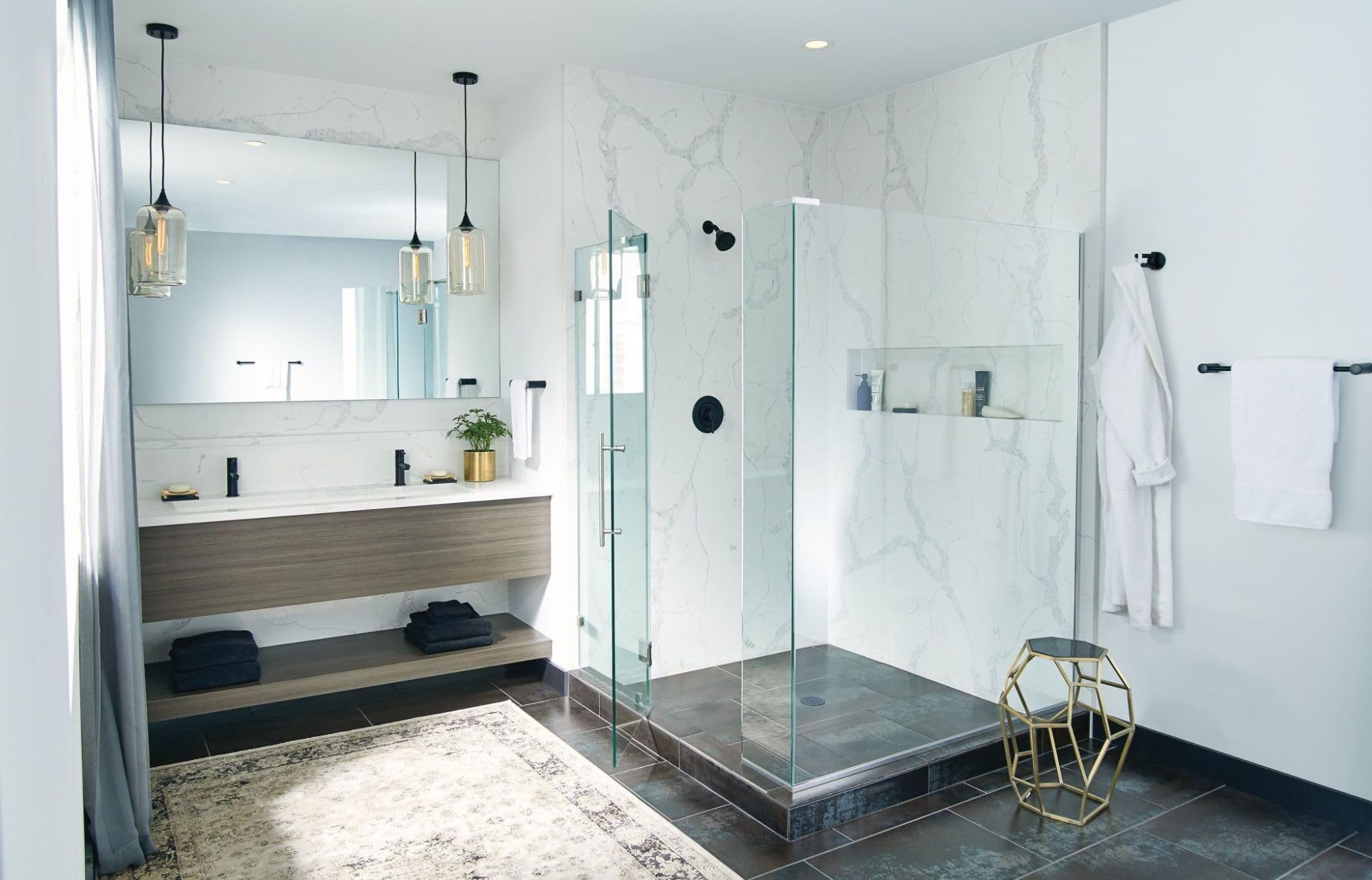 Matte black single towel bar mounted on marble tile wall next to glass shower enclosure.