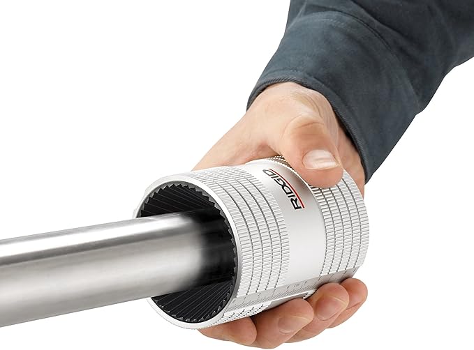 RIDGID pipe reamer with white and black grip being held around metal pipe.