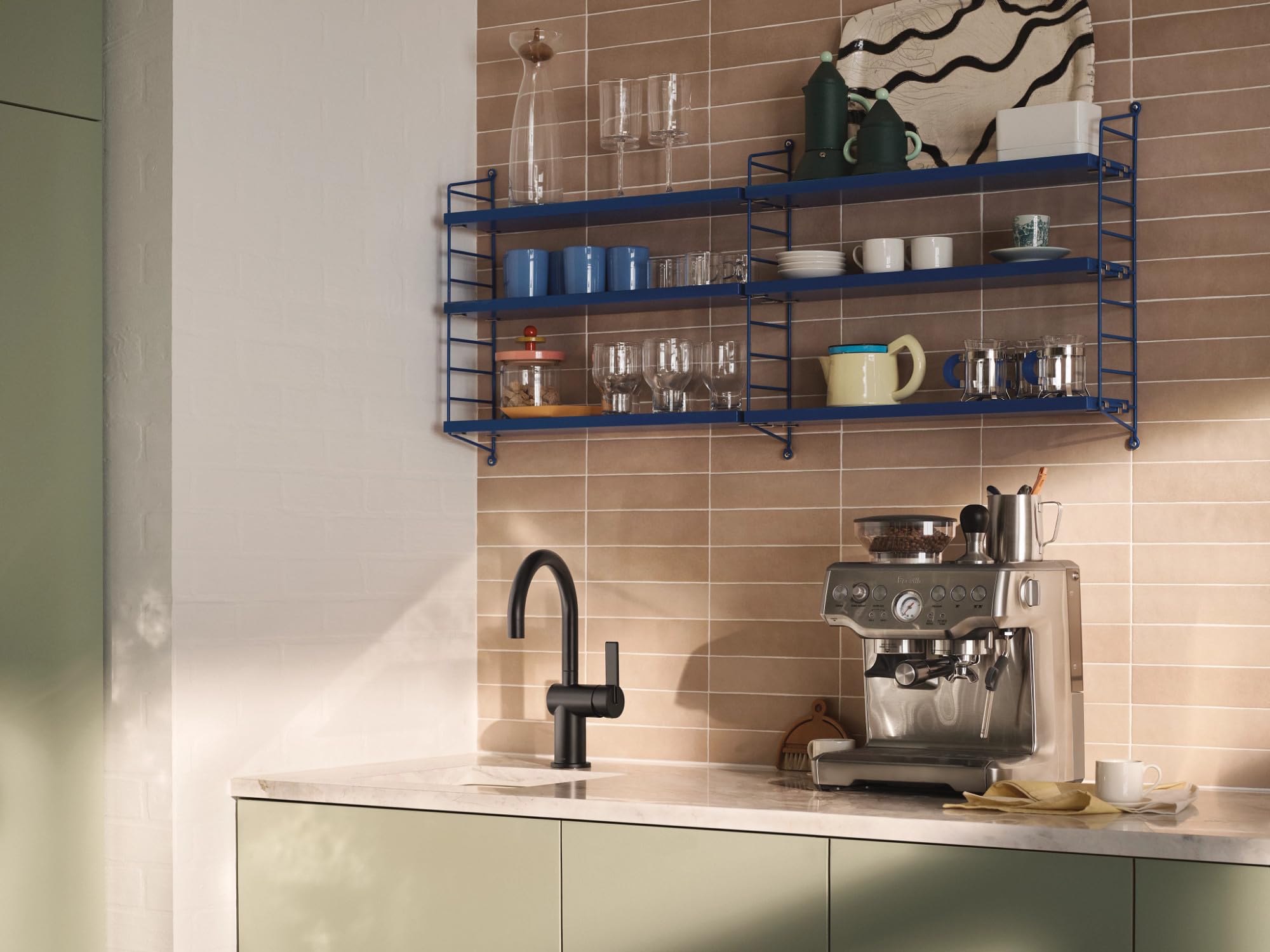 Matte black single-handle bar faucet installed above white countertop in kitchen with tile backsplash.