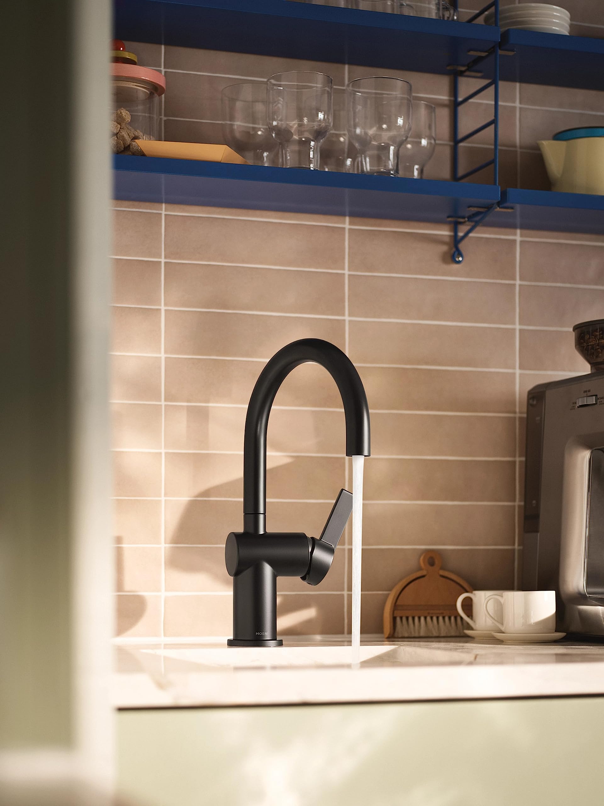 Matte black single-handle bar faucet with curved spout installed on kitchen countertop against tiled backsplash.