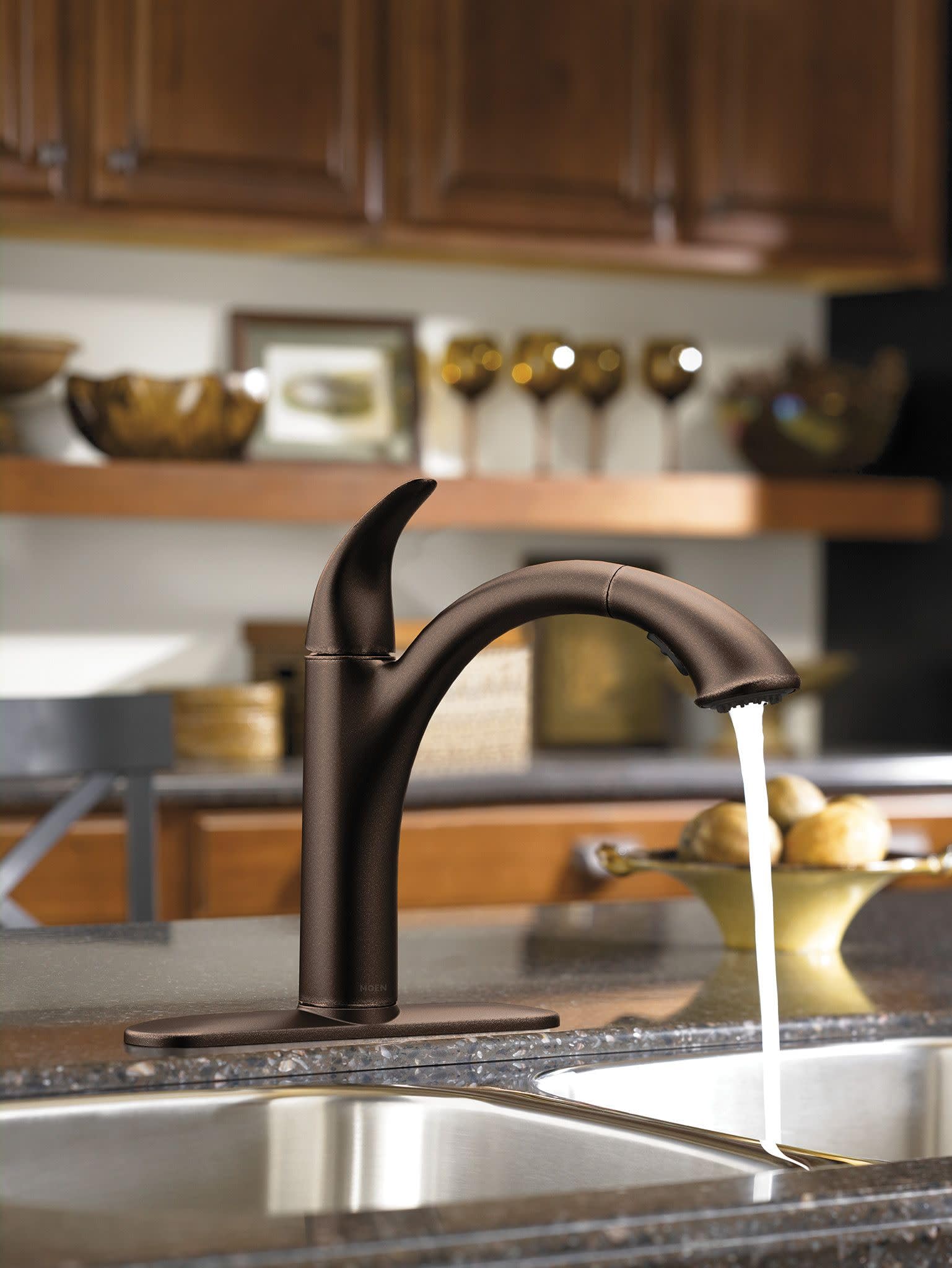 Oil rubbed bronze single-handle kitchen faucet with pullout spout and deck plate, shown installed above stainless steel sink.