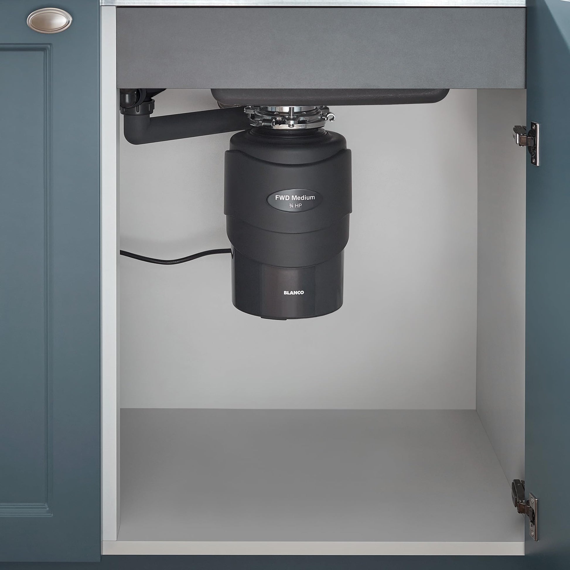 Black Blanco food waste disposal unit installed under kitchen sink with drain pipe and power cord visible.