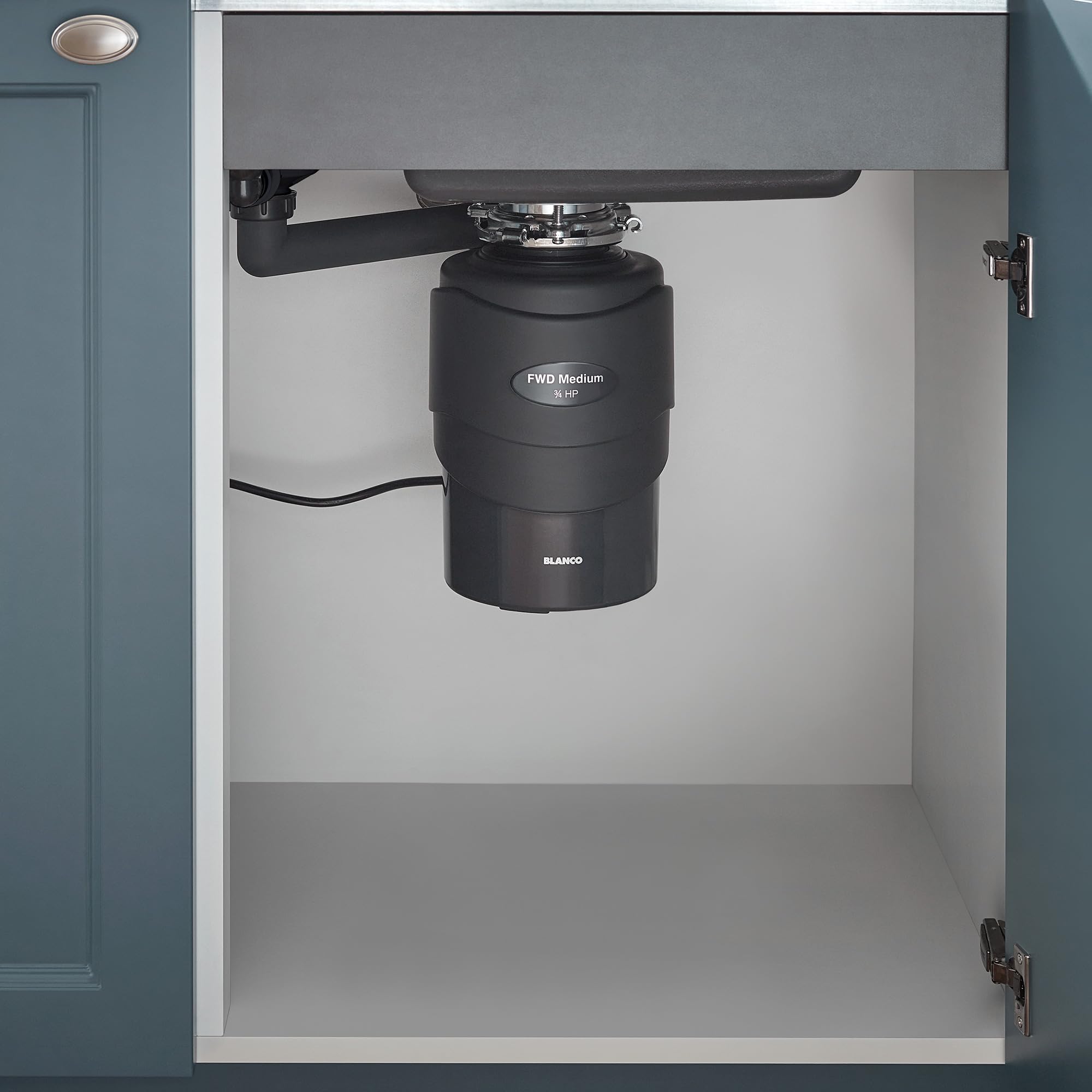 Black Blanco food waste disposal unit installed under kitchen sink with drain pipe and power cord visible.