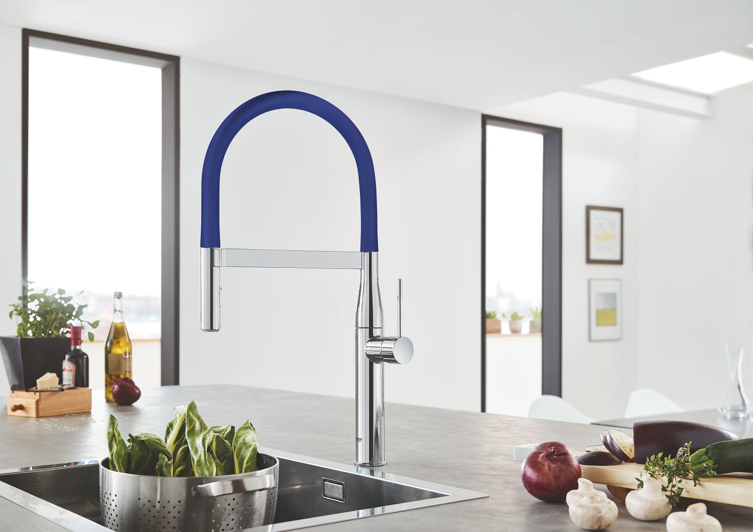 Grohe Essence kitchen faucet with blue pull-down hose and chrome finish mounted above stainless steel sink.