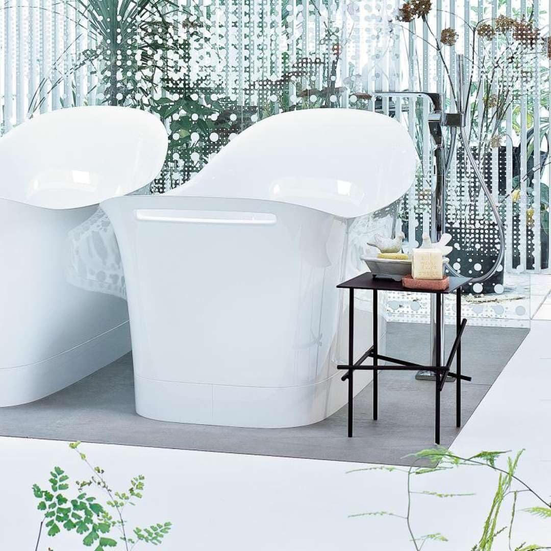 White freestanding bathtub with curved sides and integrated rim, displayed in bathroom setting.