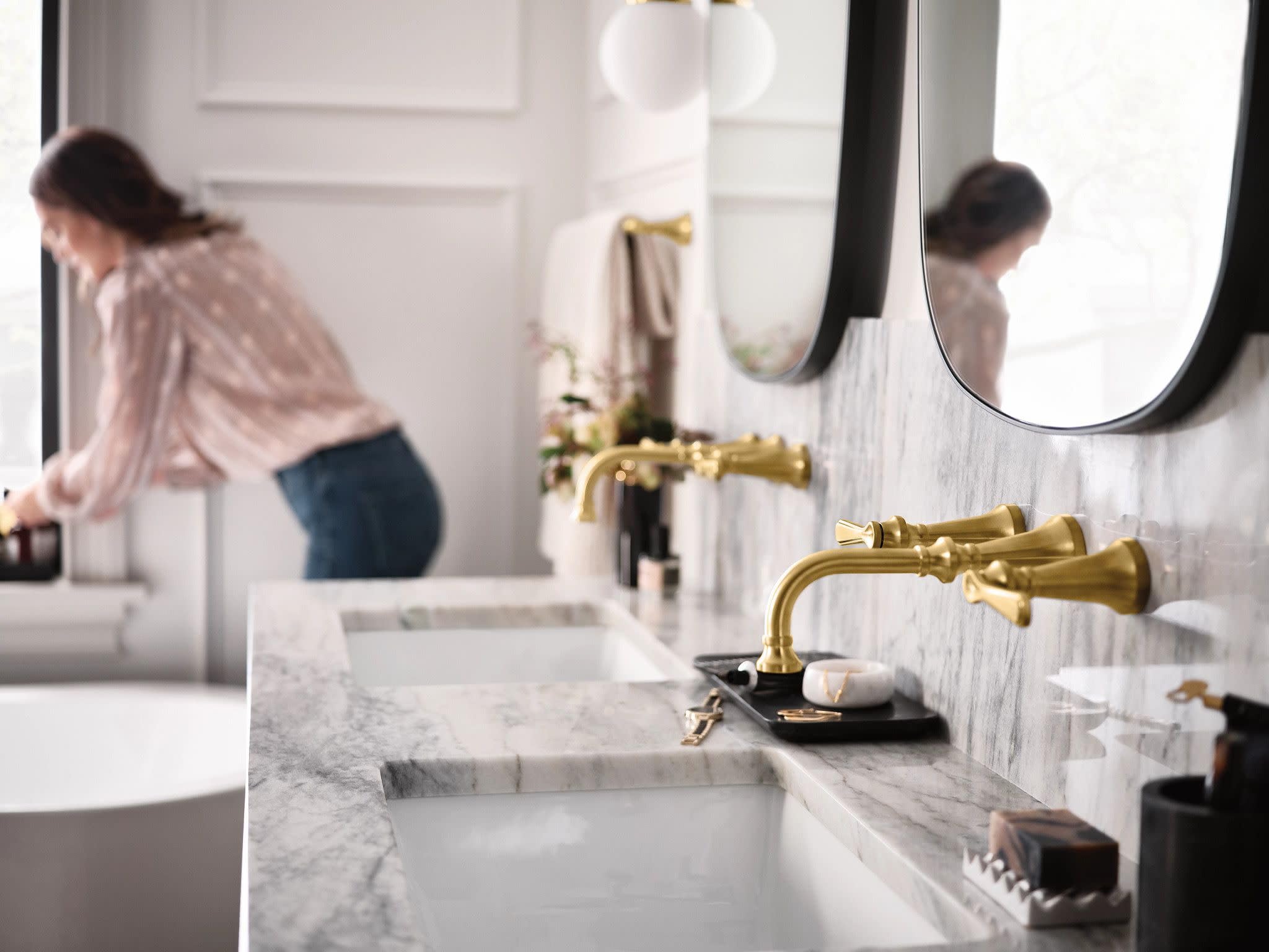Brushed gold widespread bathroom faucet with traditional lever handles mounted on marble countertop.