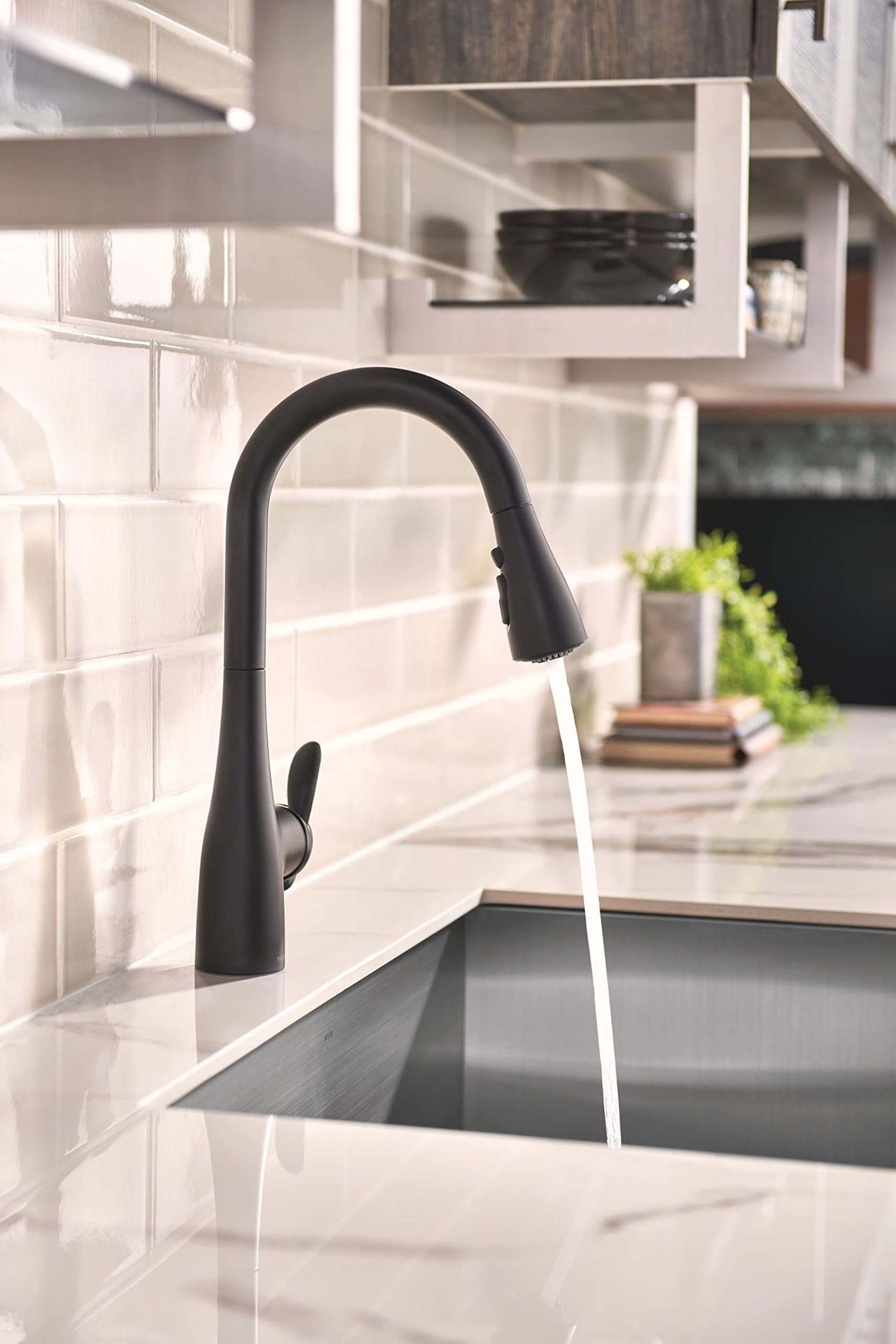 Matte black pulldown kitchen faucet with curved spout and single lever handle over stainless steel sink.