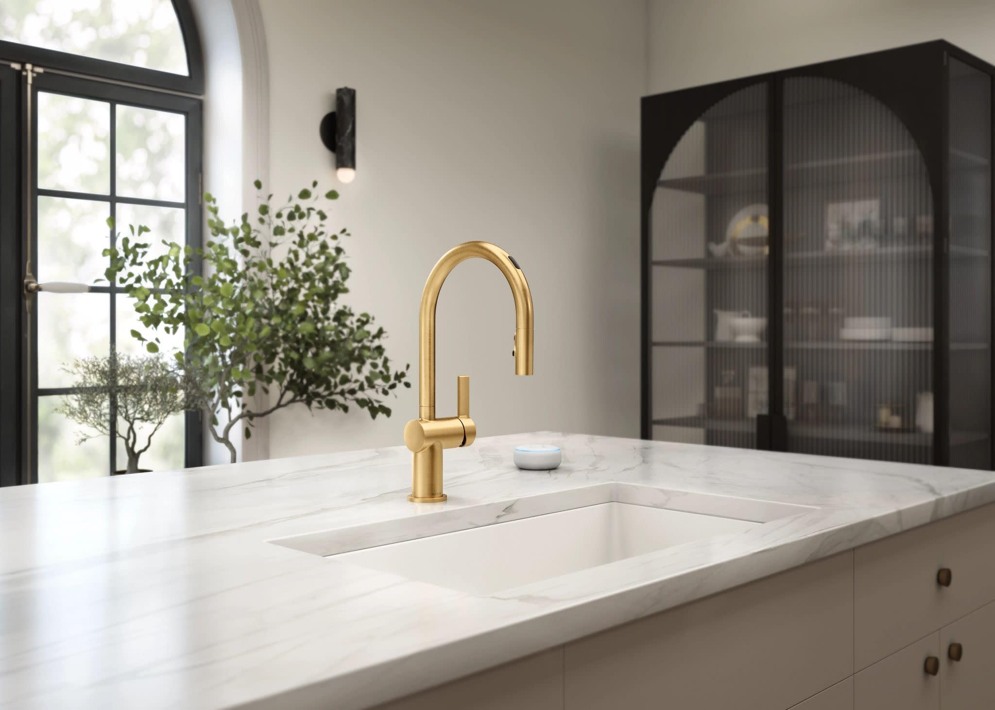 Brushed gold pulldown kitchen faucet with curved spout installed above white countertop sink.
