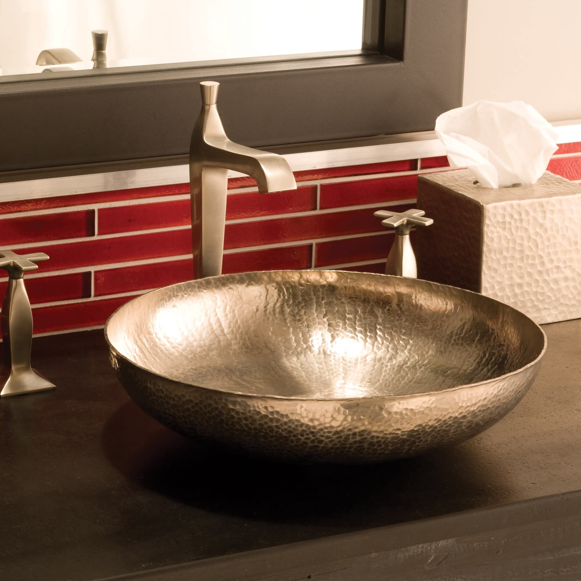 Hammered copper vessel sink with bowl shape and textured finish on dark countertop.