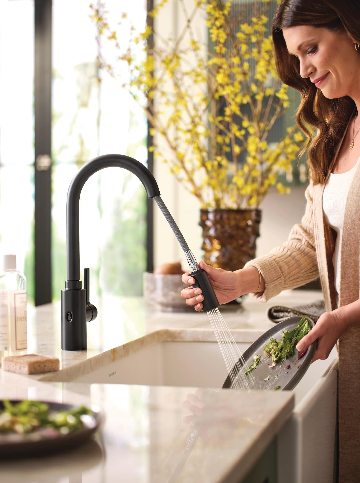 Matte black high-arc pulldown kitchen faucet with touchless wave sensor and flexible spray head over sink.