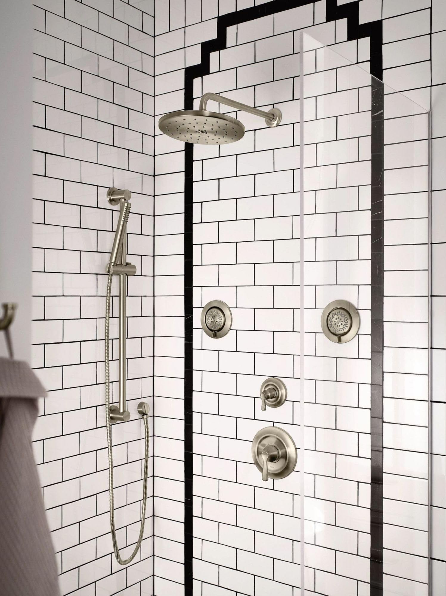 Brushed nickel shower valve trim kit with overhead rainhead, handheld wand, and four body jets installed on subway tile showe