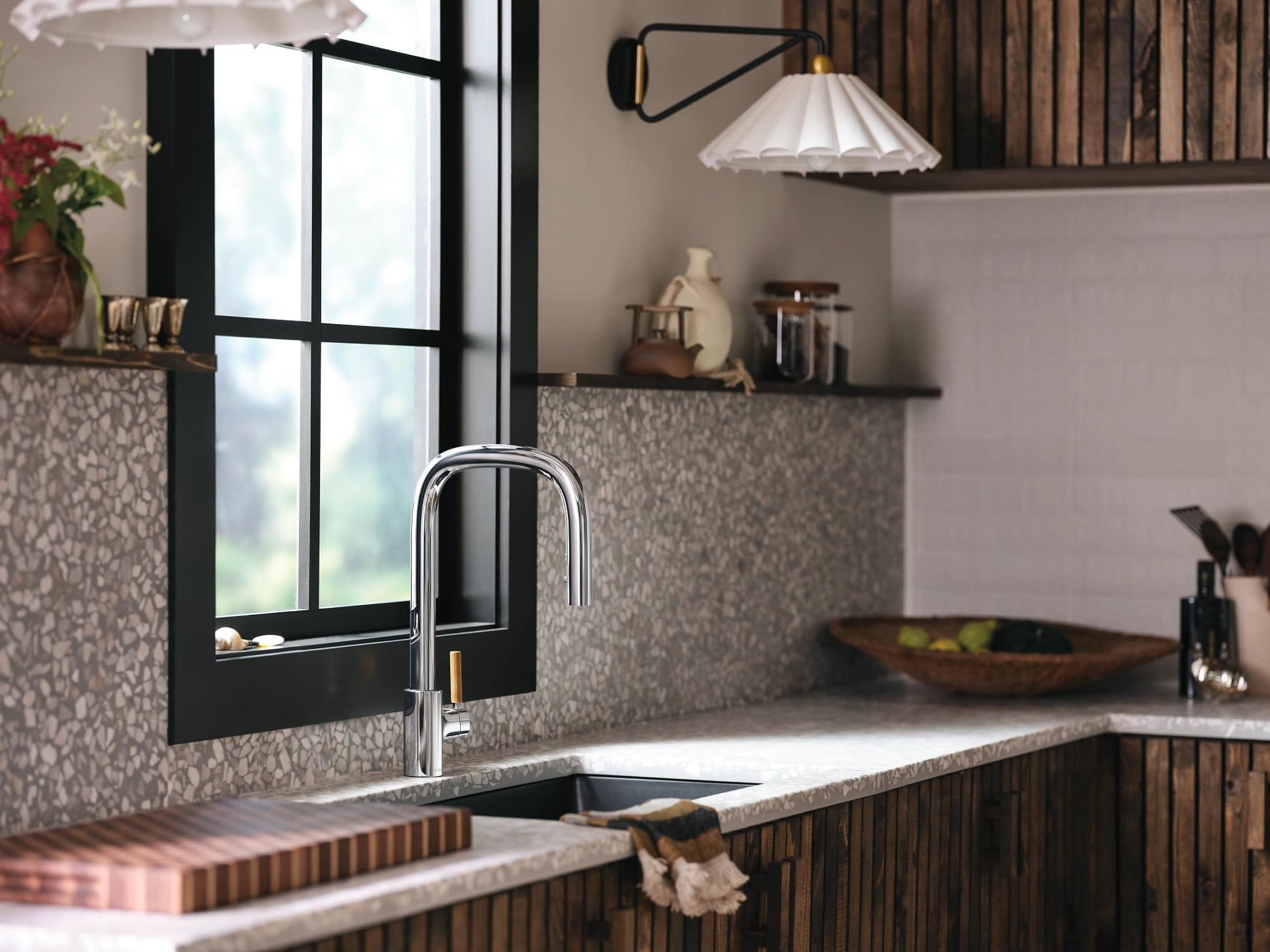 Chrome pulldown kitchen faucet with single handle mounted above sink in modern kitchen setting.