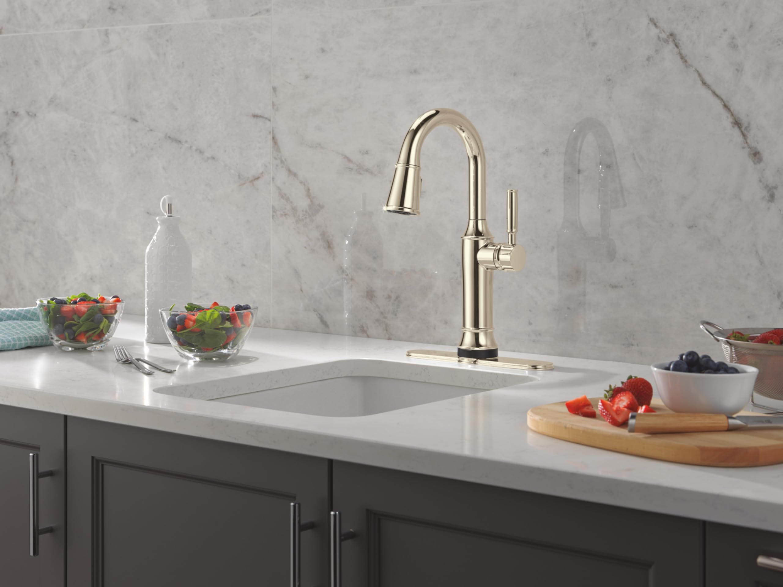 Champagne bronze pulldown kitchen faucet with curved spout and single handle mounted on white countertop.