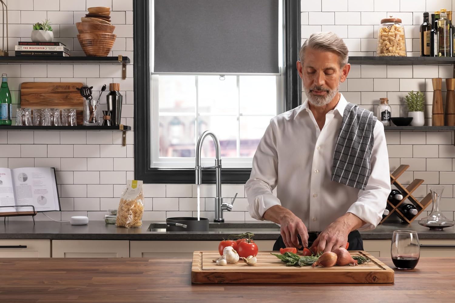 Man preparing vegetables at kitchen counter with modern faucet and white subway tile backsplash.