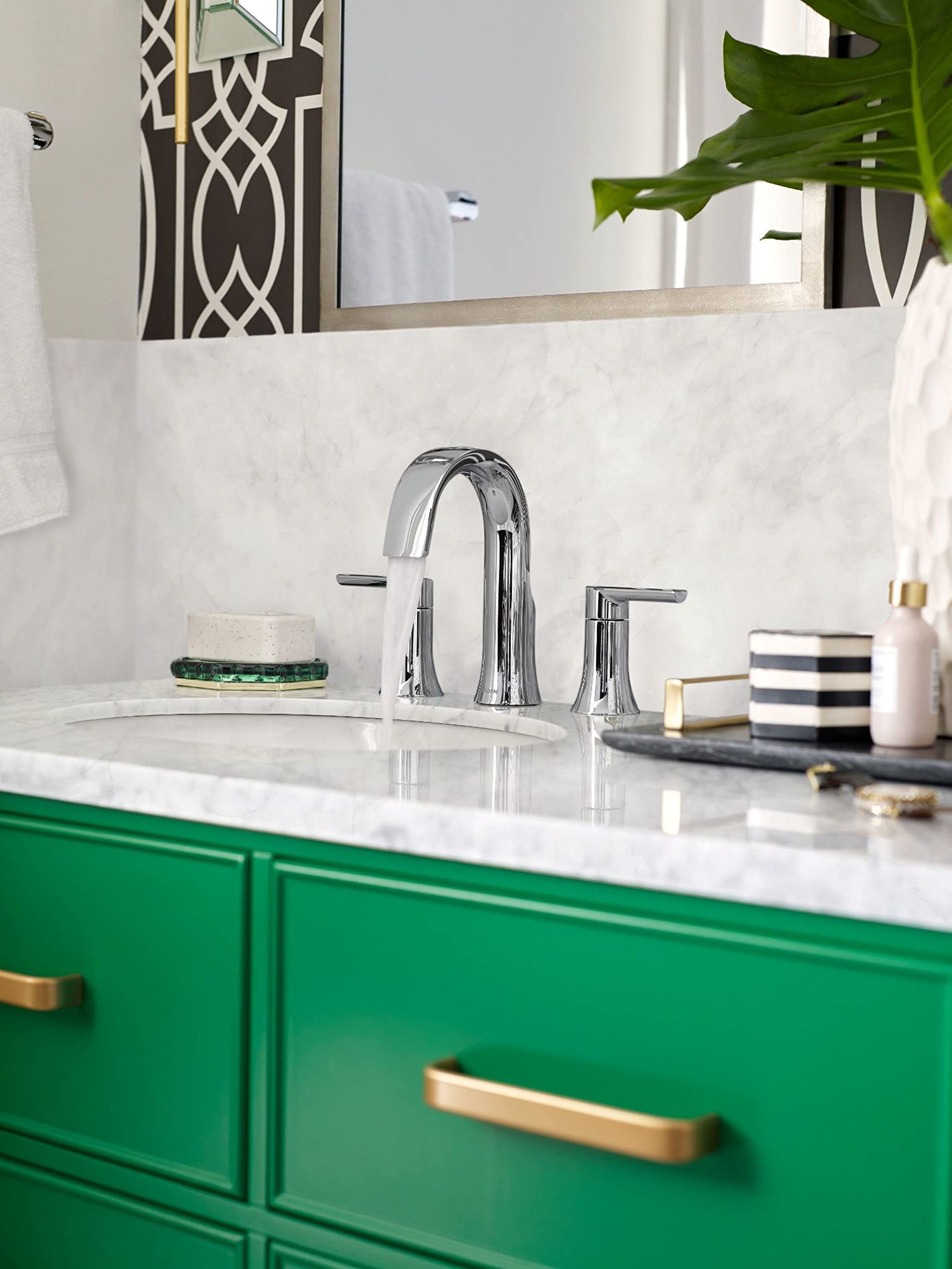 Chrome widespread bathroom faucet with arched spout and two lever handles installed on marble countertop.