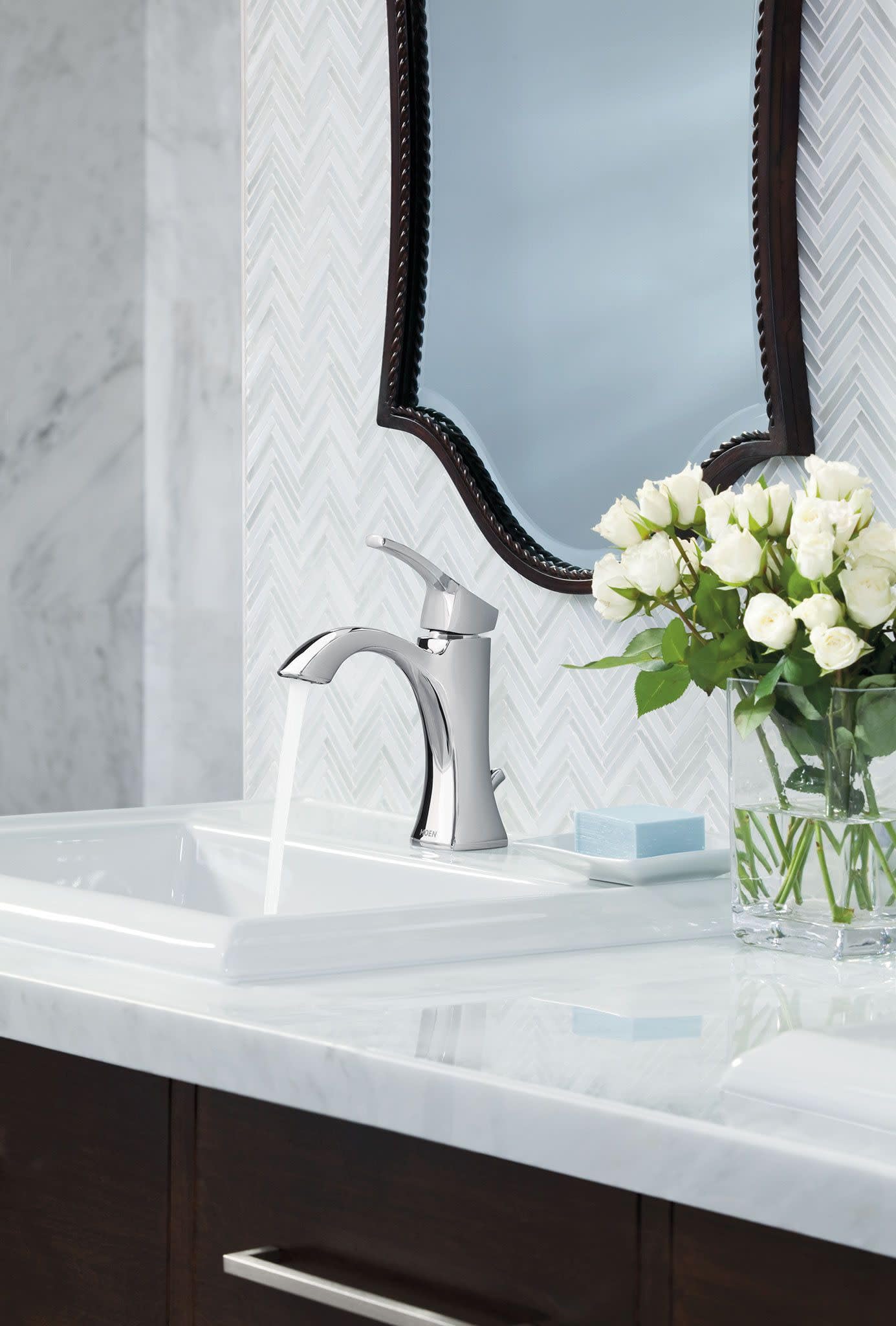 Chrome single-handle bathroom faucet with curved spout mounted on white sink countertop.
