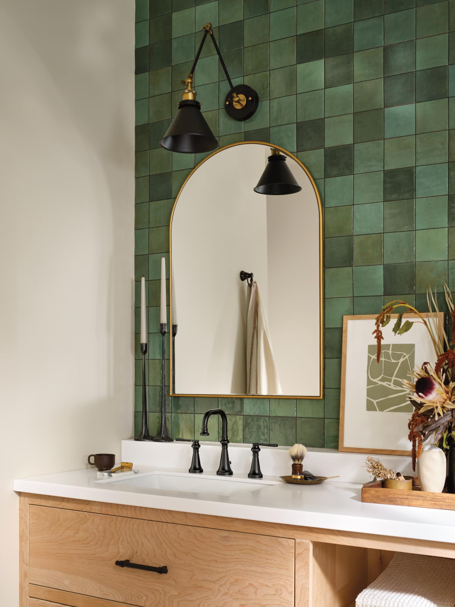 Matte black two-handle widespread bathroom faucet with high arc spout and lever handles installed on white sink.