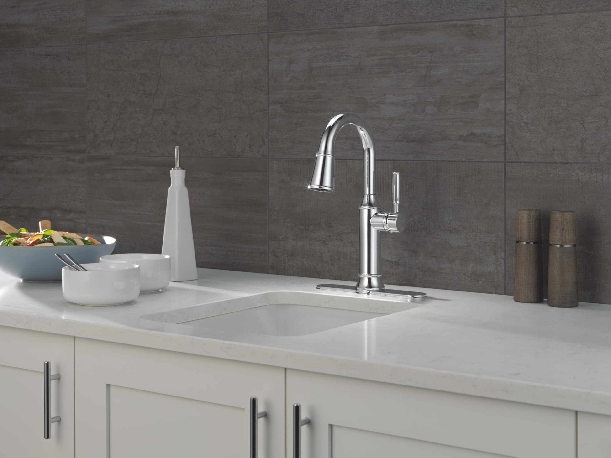 Stainless steel pulldown kitchen faucet with curved spout installed above white countertop sink.
