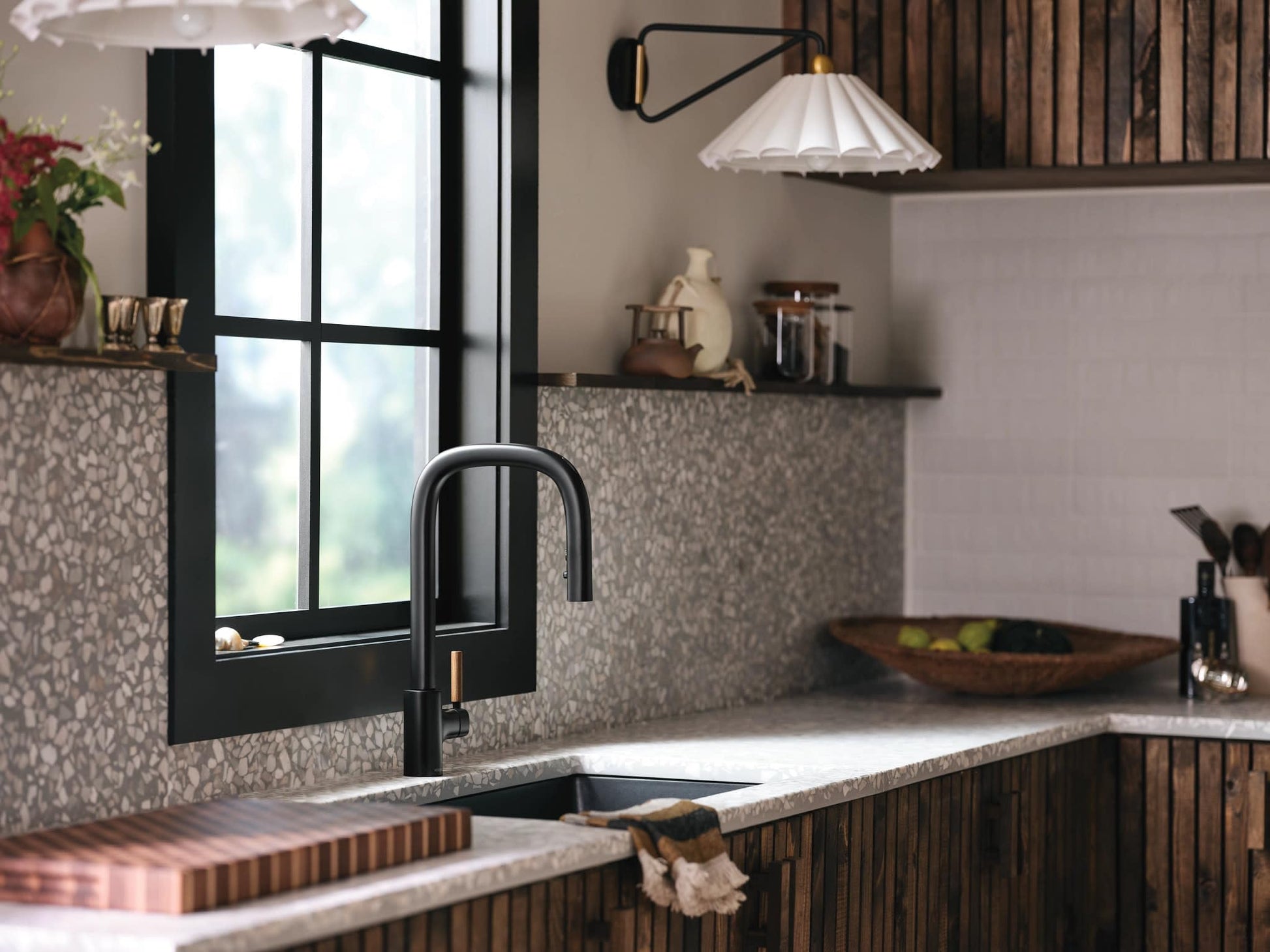 Matte black single-handle kitchen faucet with pulldown spray mounted above sink in modern kitchen.