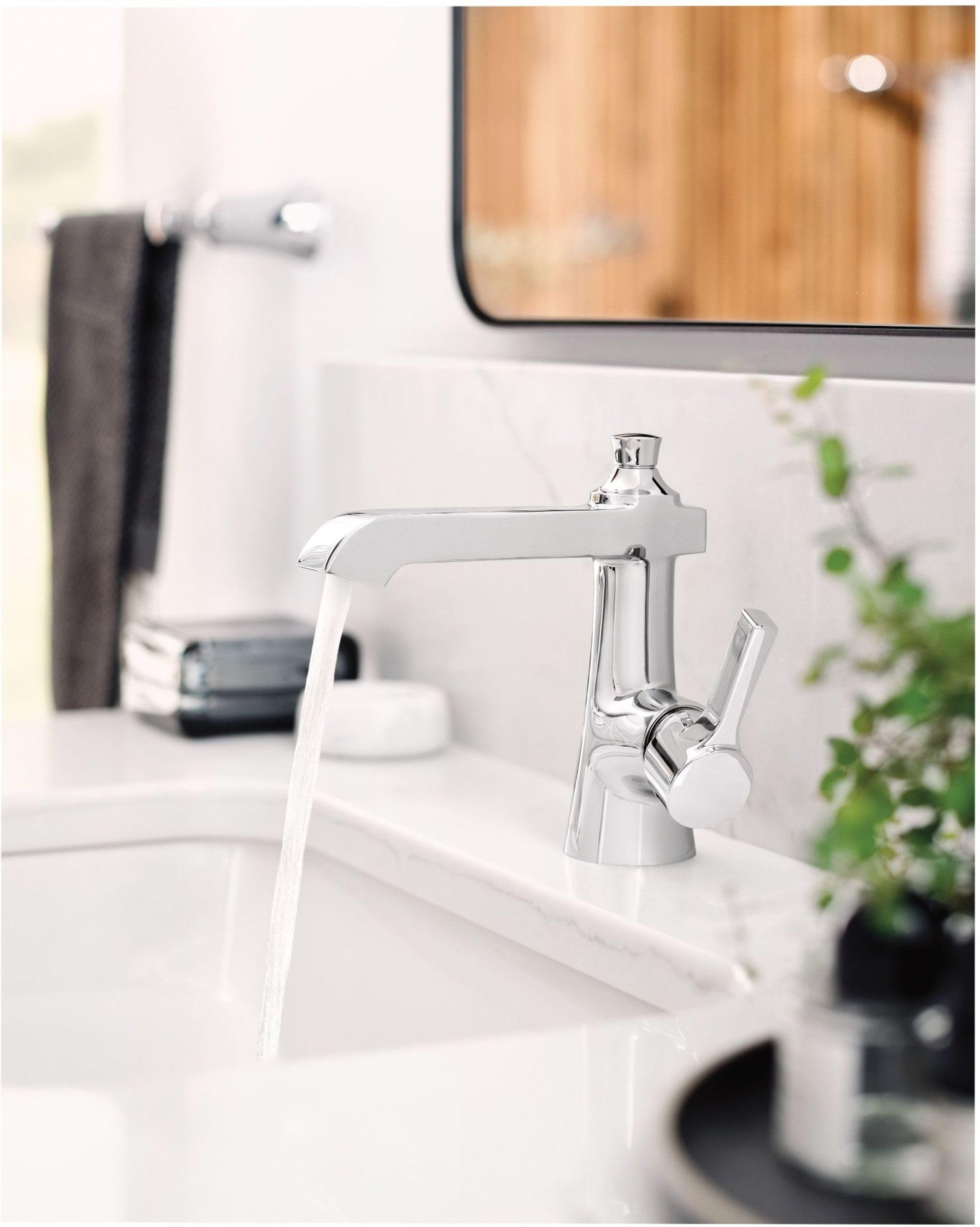 Chrome single-handle bathroom faucet with curved spout and lever handle mounted on white sink basin.