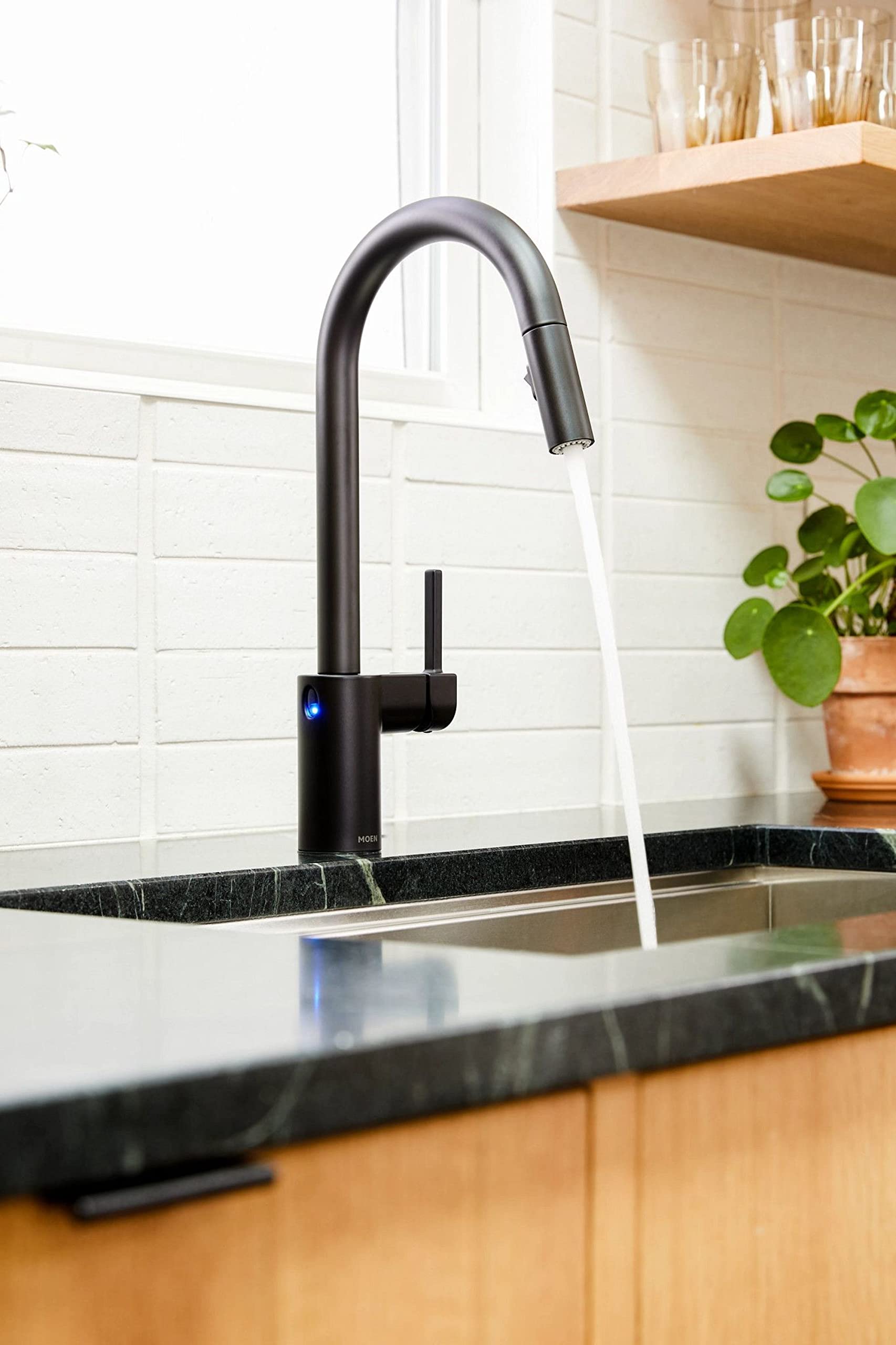 Matte black high-arc pulldown kitchen faucet with sensor activation and pulldown spray head over sink.