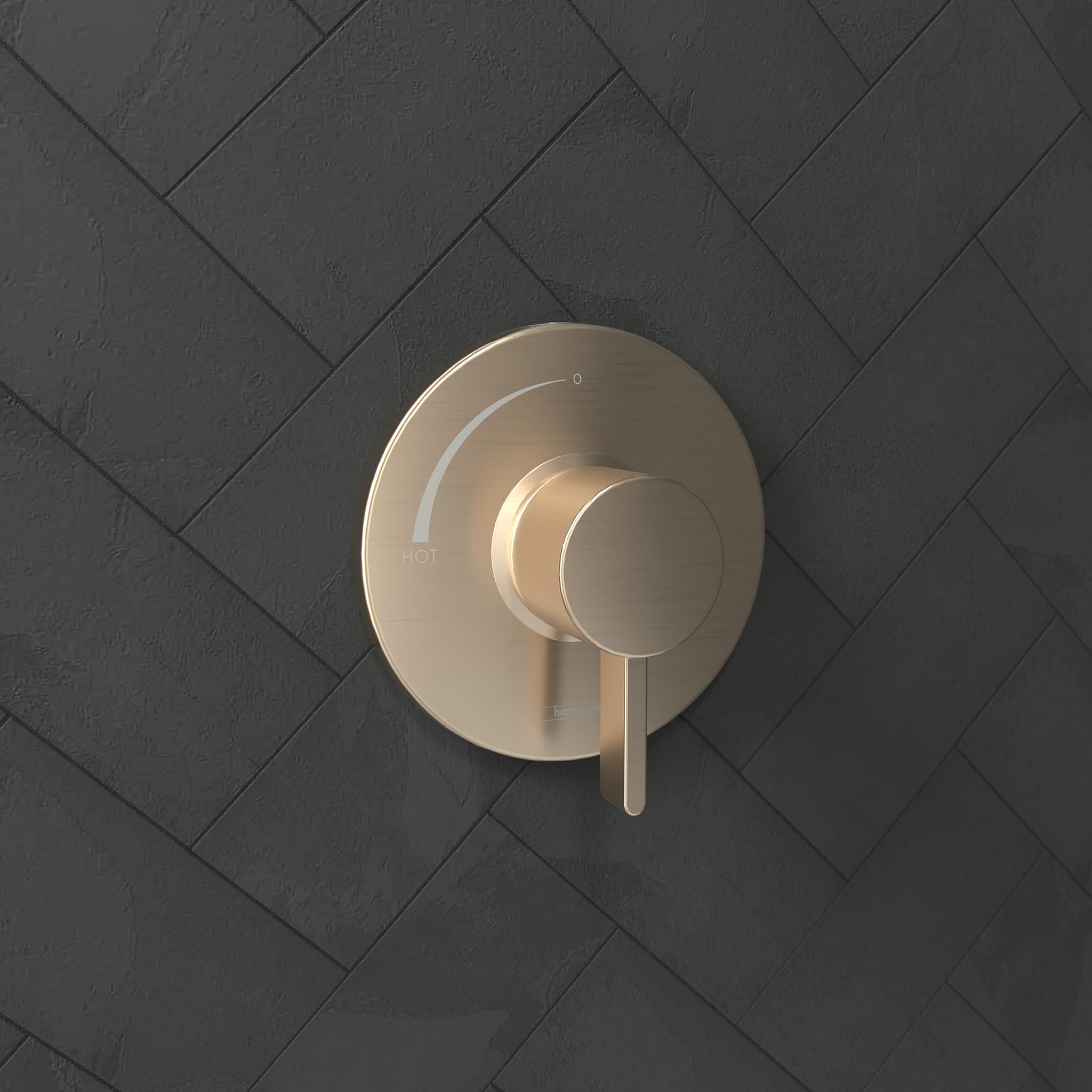Brushed bronze round pressure balance valve trim with circular backplate and single lever handle mounted on herringbone tile 