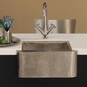 Hammered copper undermount sink with textured surface and chrome dual-handle faucet installed in countertop.