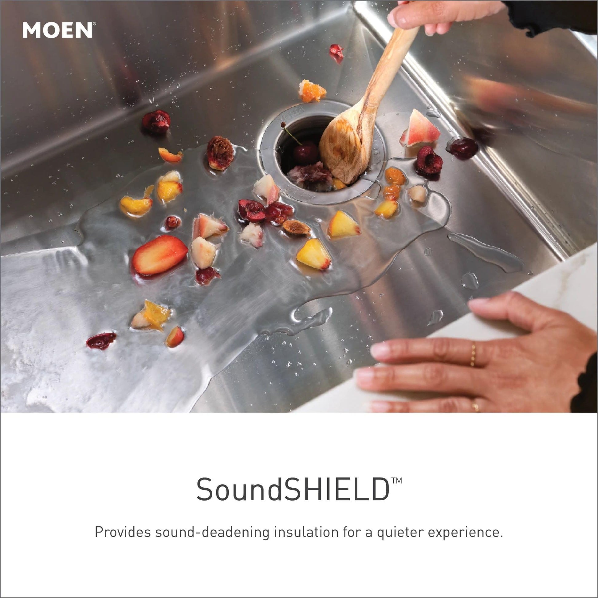 Stainless steel single bowl undermount kitchen sink with fruit and colander inside, hands rinsing produce under running water