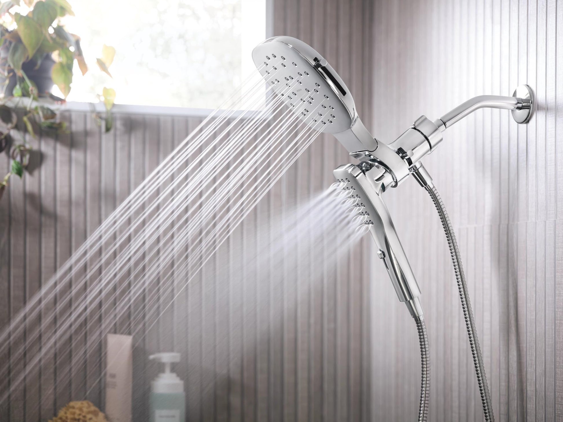 Chrome shower system with 7-inch square rain head and detachable hand shower on flexible hose, both spraying water.