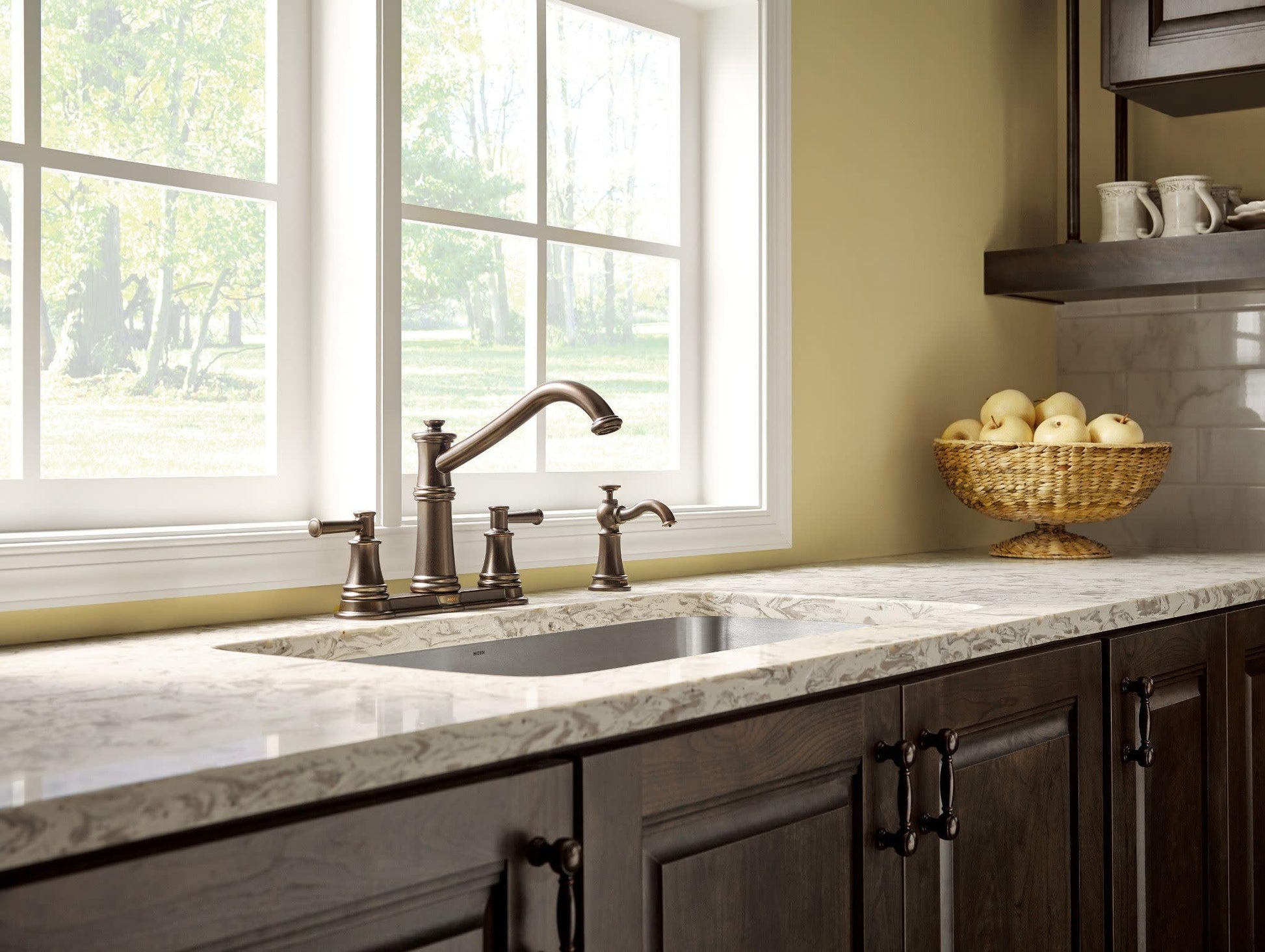 Oil rubbed bronze two-handle kitchen faucet with high arc spout and side spray on marble countertop.