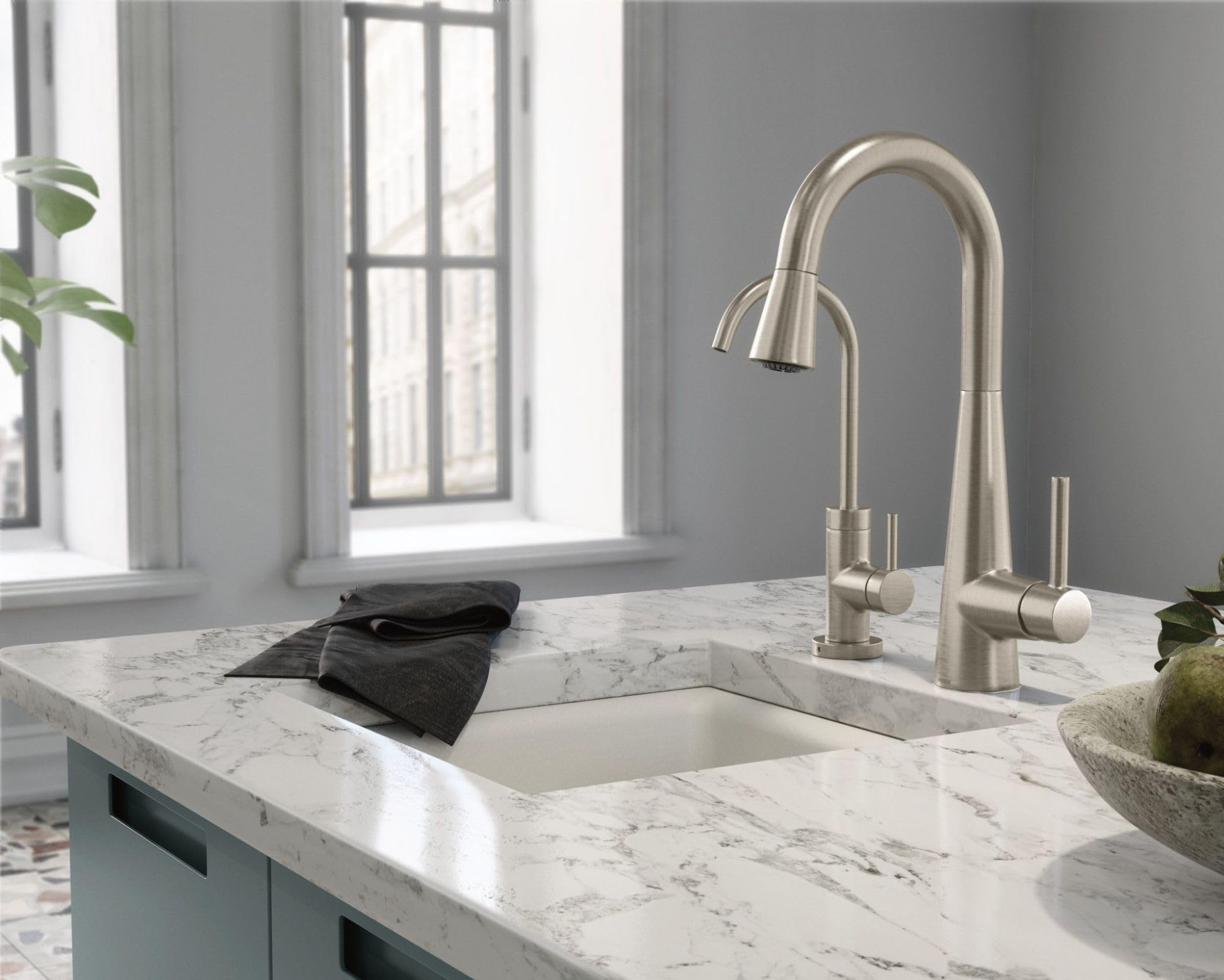 Spot-resistant stainless steel kitchen faucet with pull-down spray head and curved spout mounted on marble countertop.