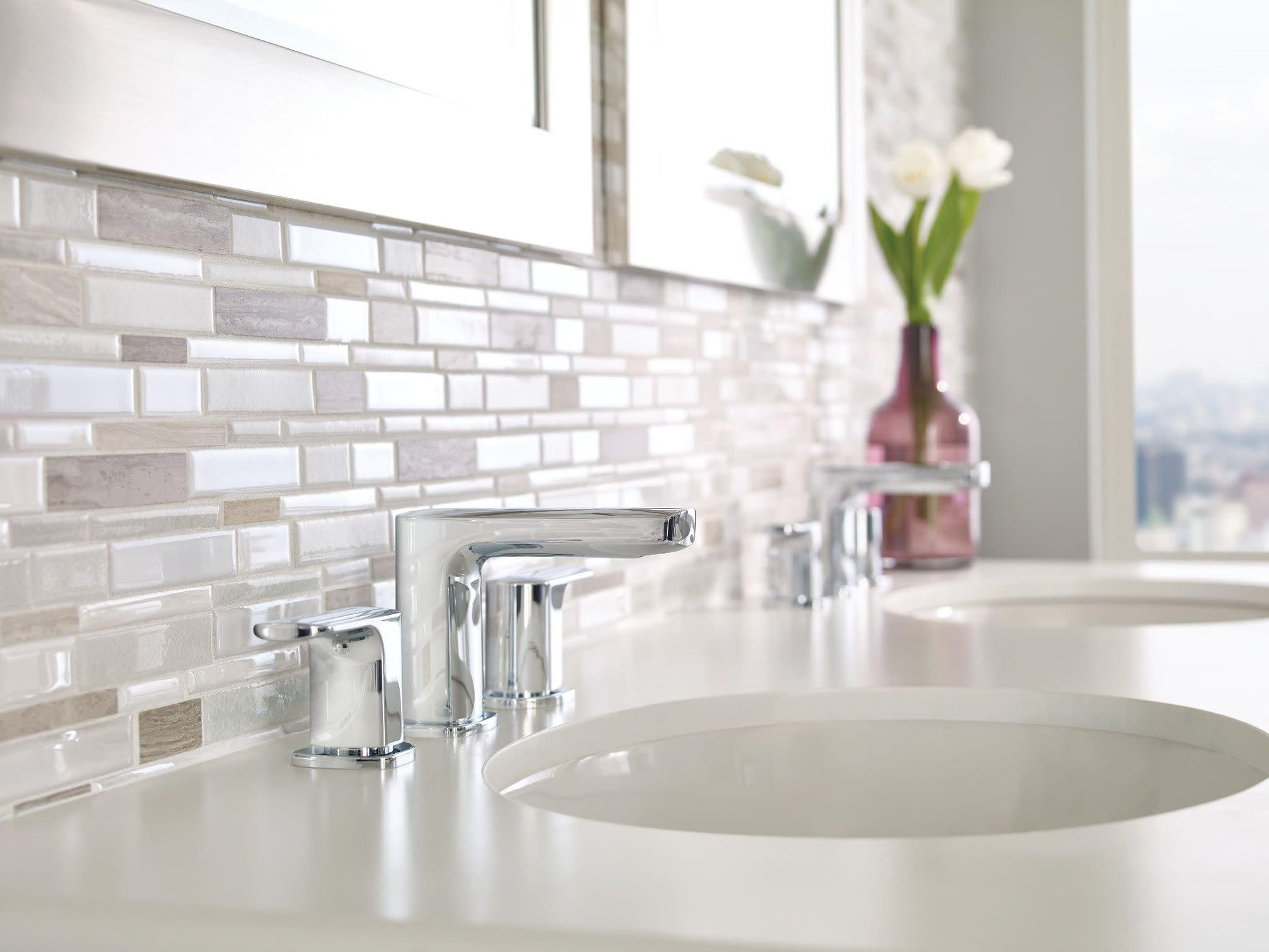 Chrome two-handle widespread bathroom faucet with angular spout mounted on white countertop.