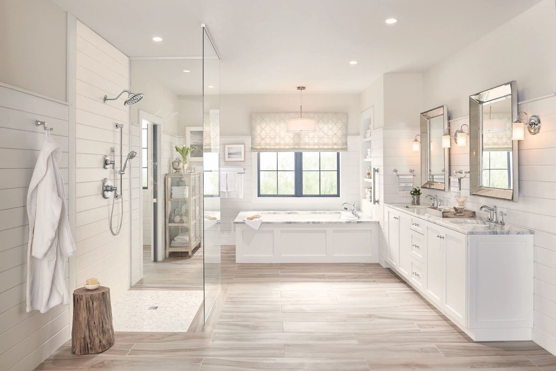 Chrome two-handle deck-mounted roman tub faucet with hand shower mounted on white bathroom tub surround.