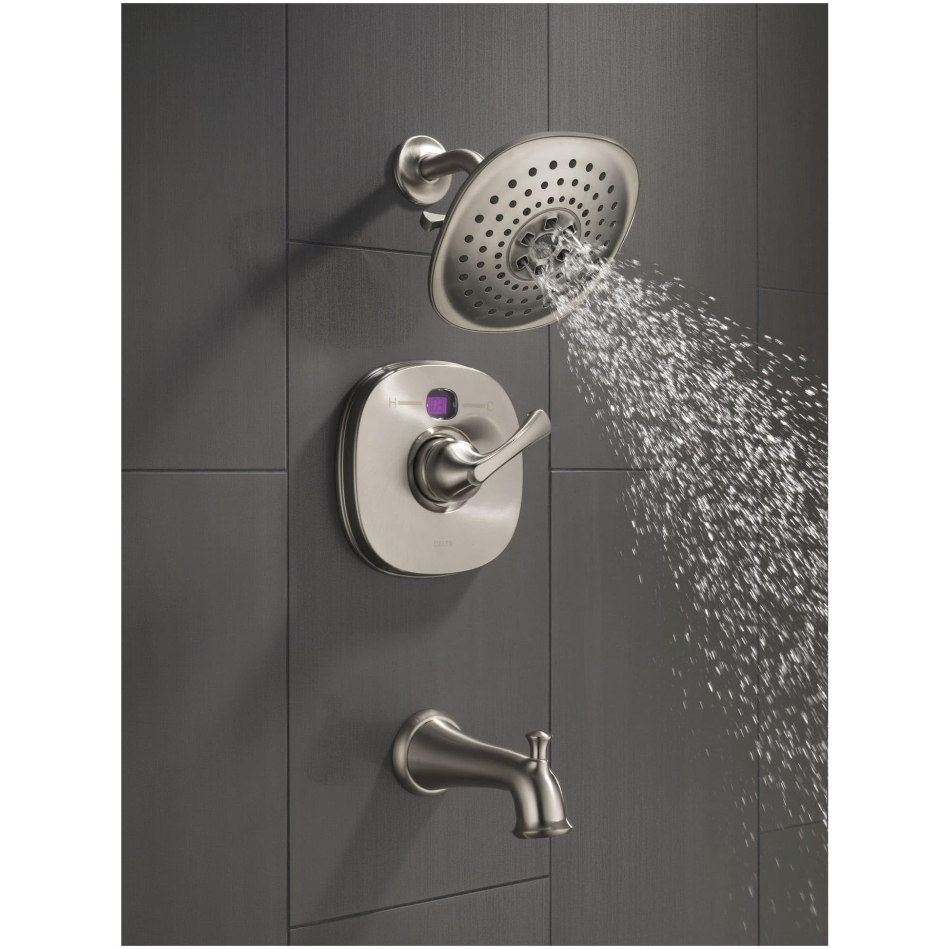Polished nickel shower flange with perforated head mounted on gray tile wall with control valve and tub spout below.