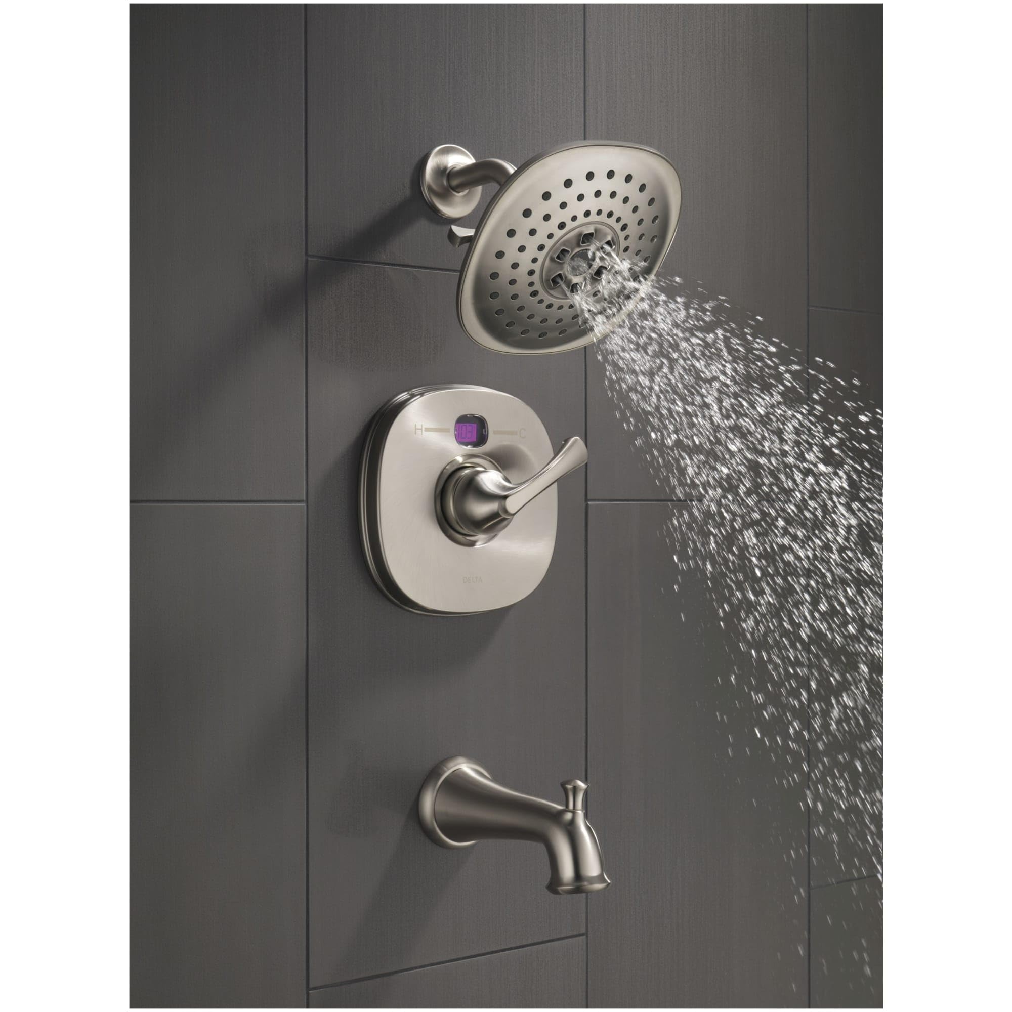 Polished nickel shower flange with perforated head mounted on gray tile wall with control valve and tub spout below.