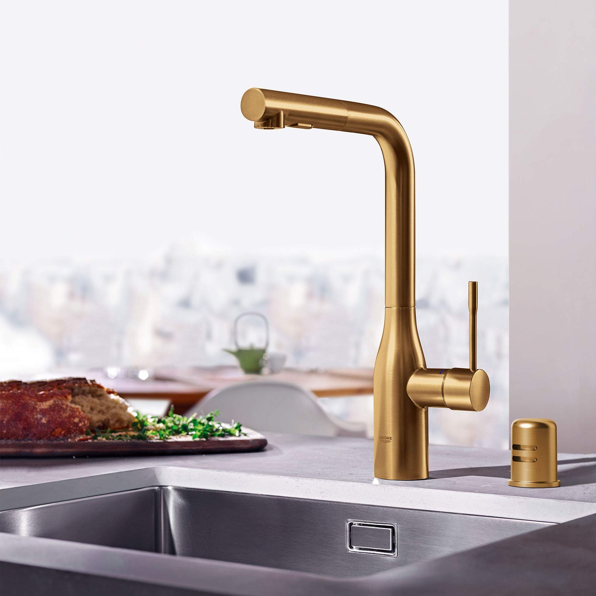 Brushed gold kitchen faucet with pull-down spout and separate air gap dispenser on sink counter.