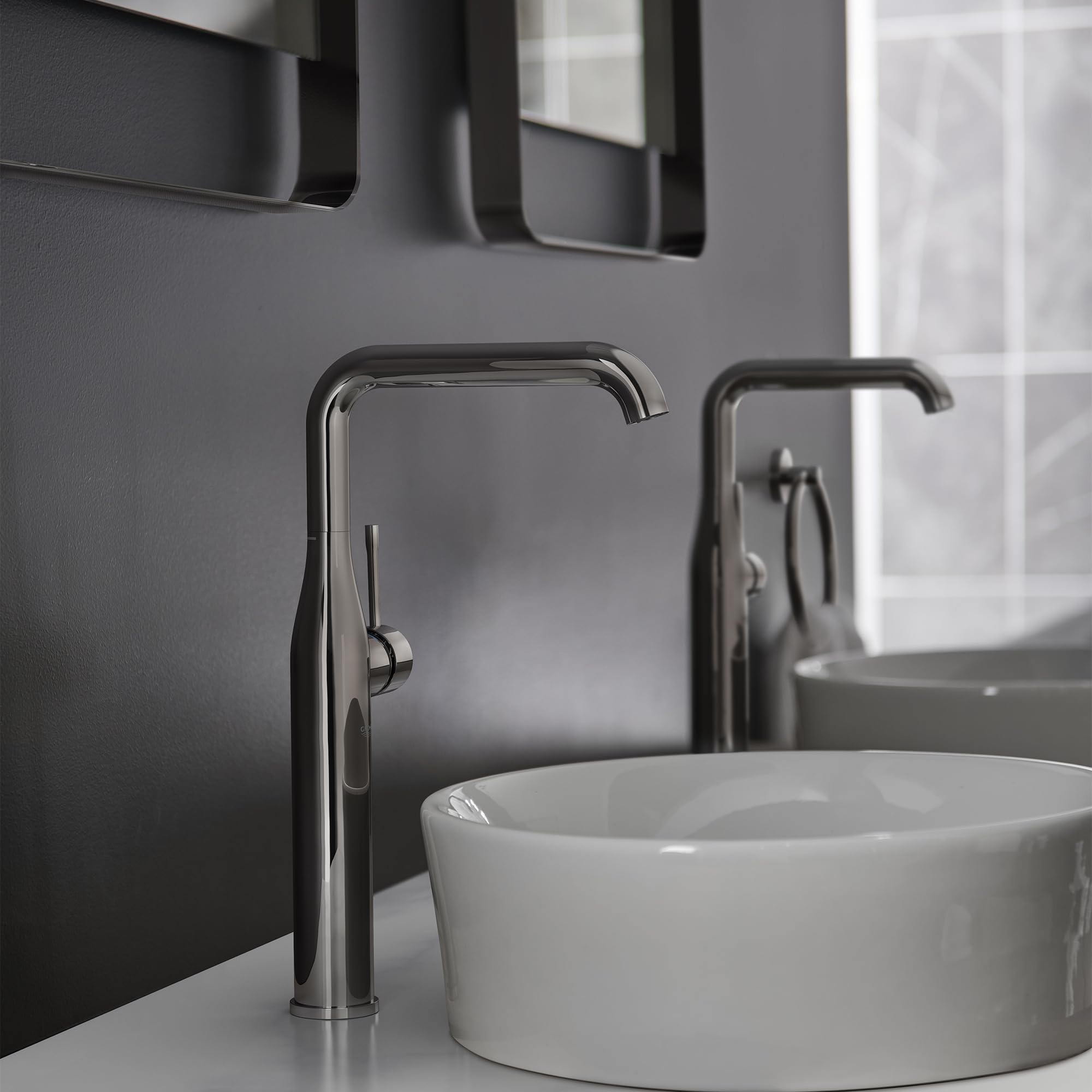 Dark graphite single-handle faucet with tall curved spout mounted next to white round vessel sink.