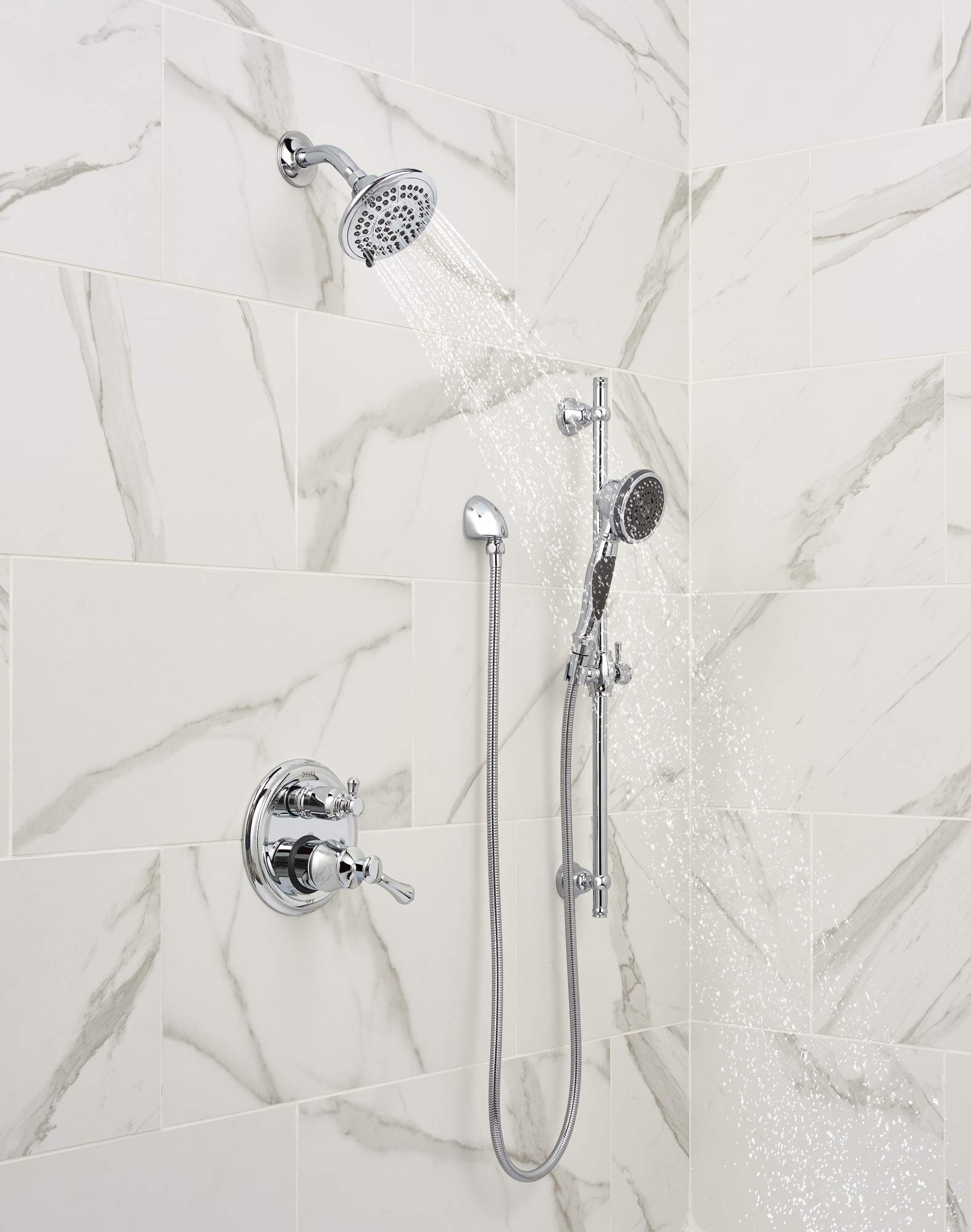 Chrome shower system with fixed overhead showerhead, handheld showerhead, and valve control mounted on marble tile wall.