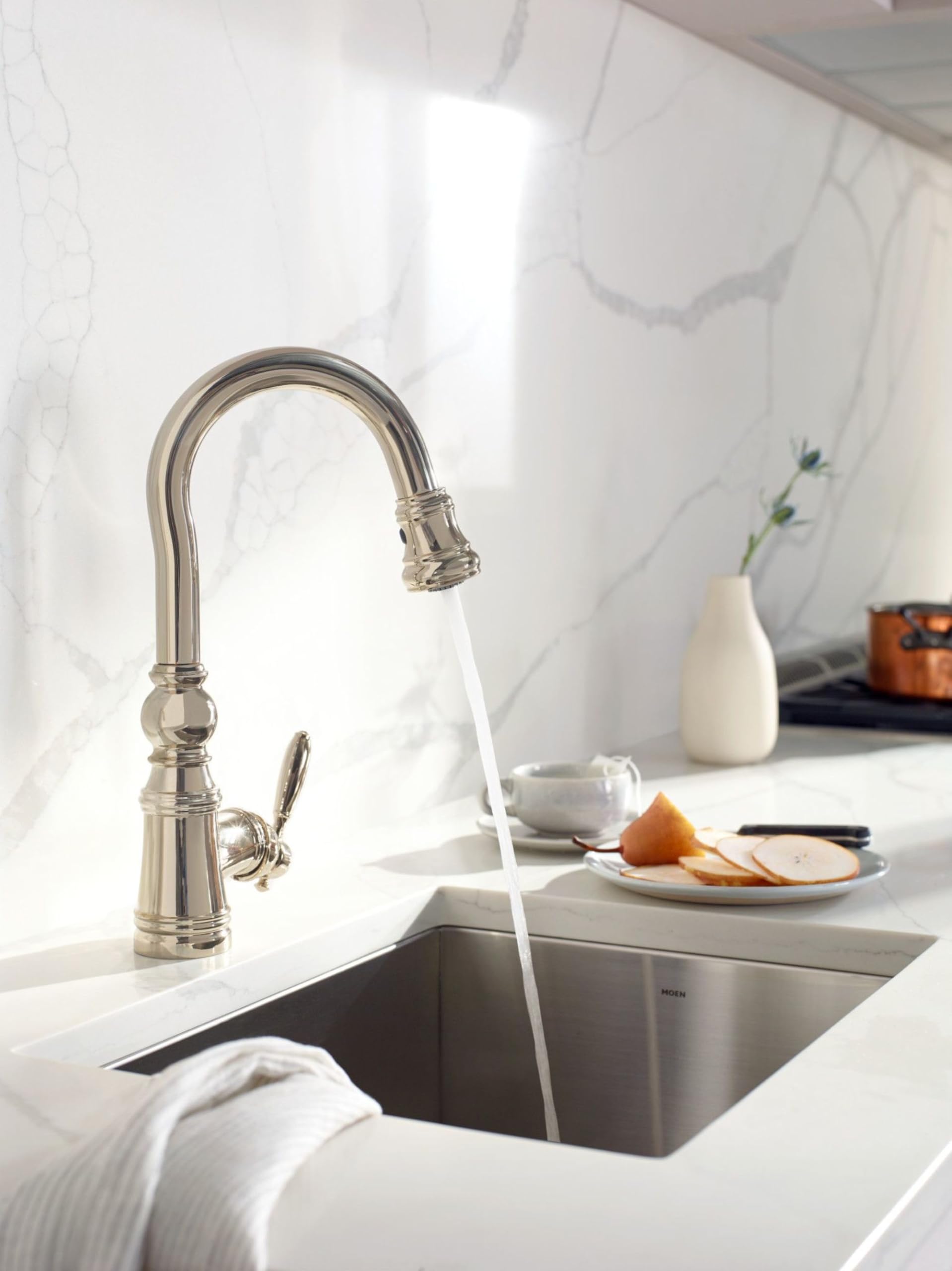 Polished nickel pulldown kitchen faucet with curved spout and single lever handle installed over sink.