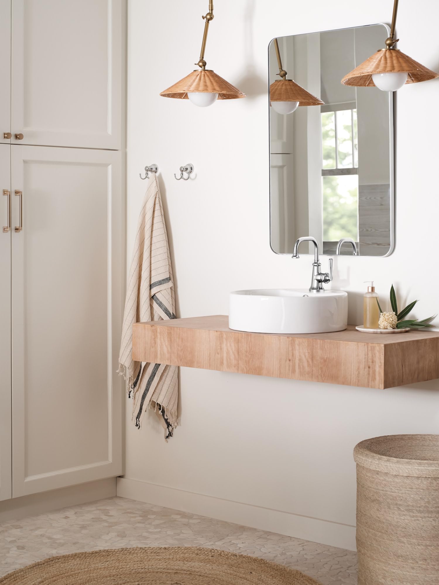Chrome single-handle faucet with curved spout mounted on white round sink in bathroom vanity.