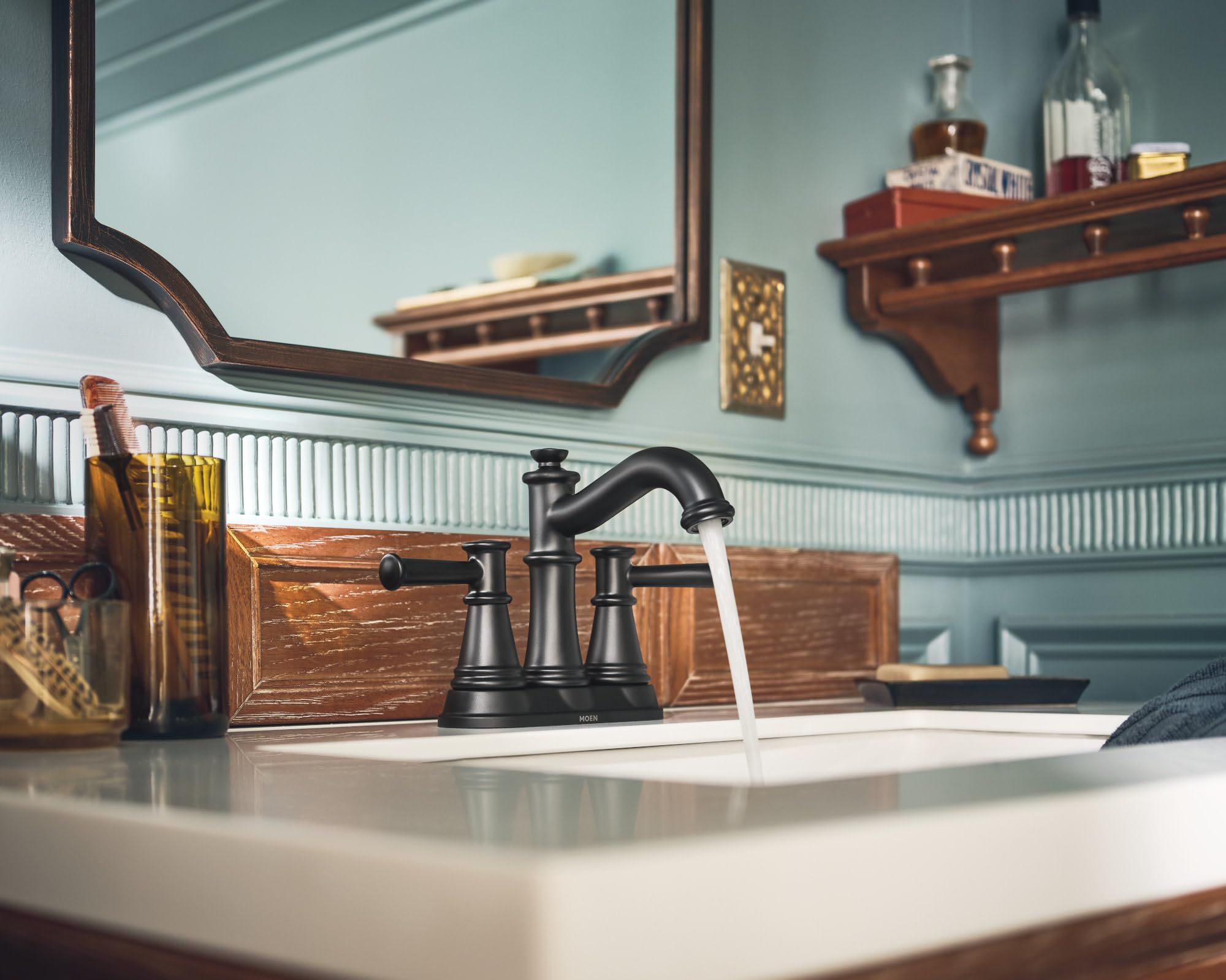 Matte black two-handle centerset bathroom faucet with curved spout and water running, installed on white sink.