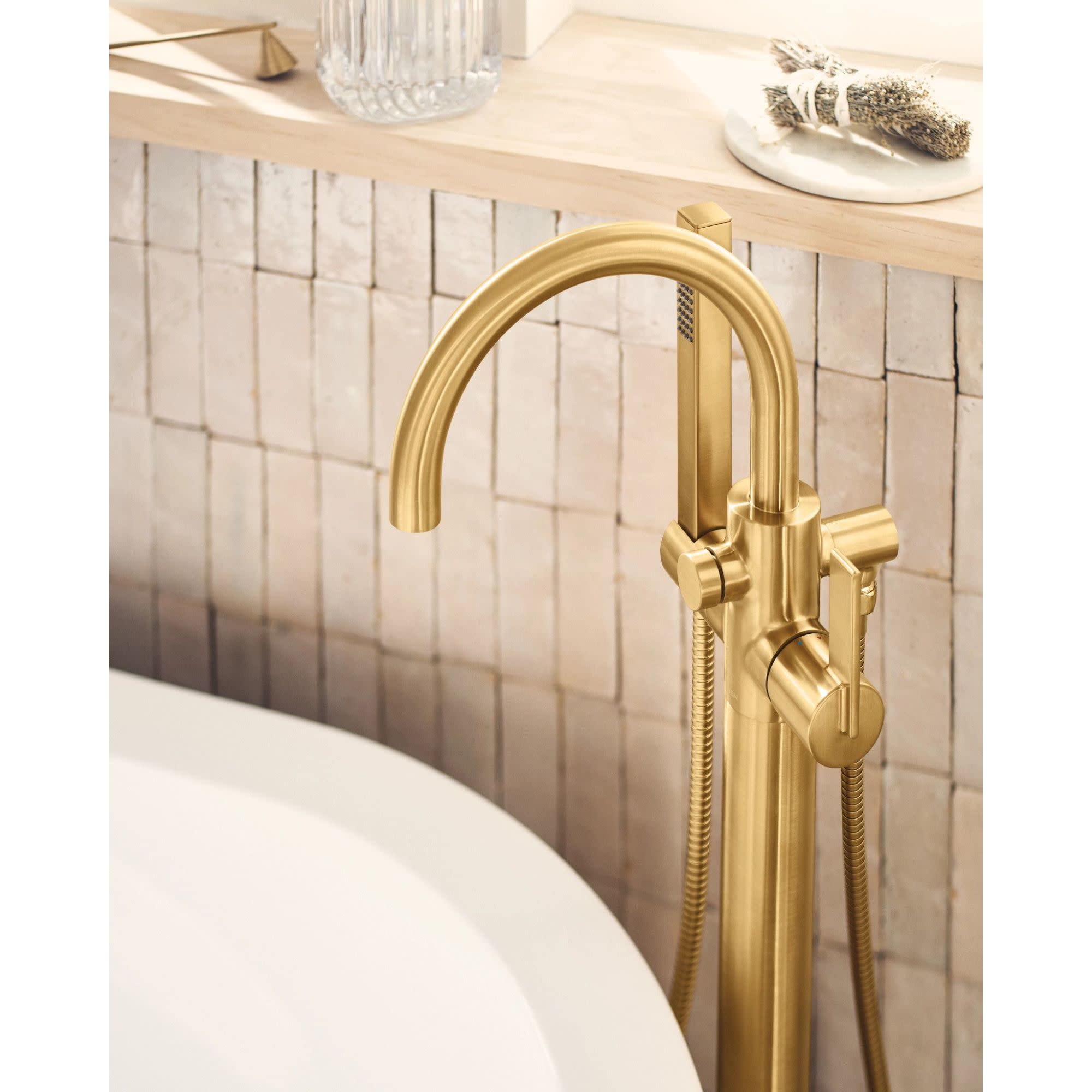 Brushed gold freestanding tub filler with arched spout, single handle, and attached handshower hose.