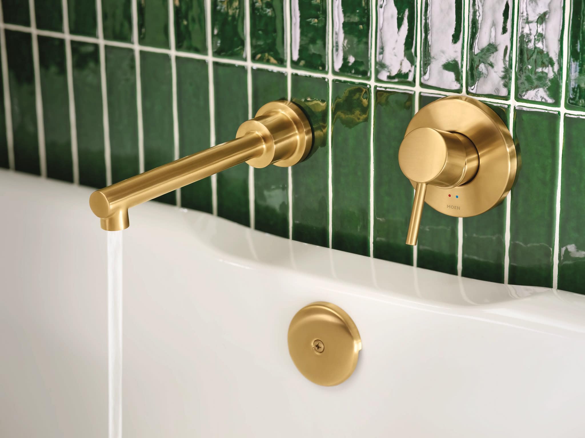 Brushed gold wall-mount tub faucet with single handle control and 10" spout extending over white bathtub edge.